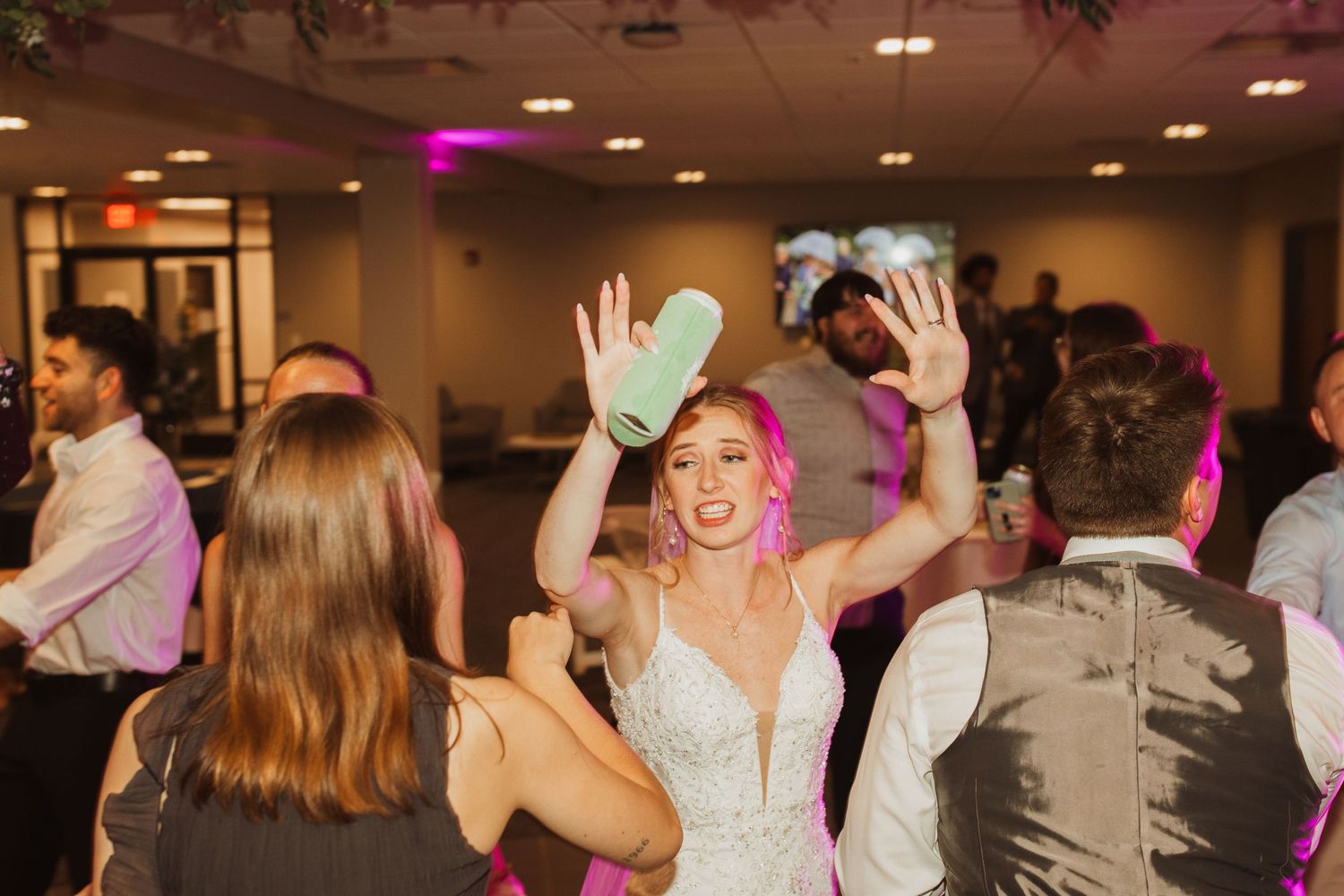 Wedding guests dancing and celebrating on a dimly lit dance floor at a reception party.
