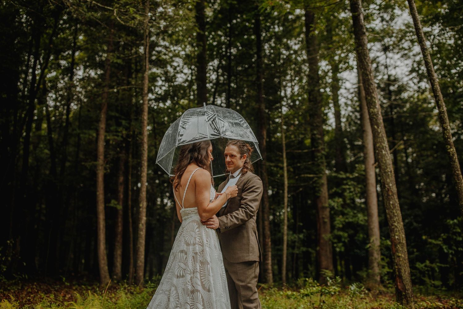 A tender moment captured between newlyweds in a misty forest setting.