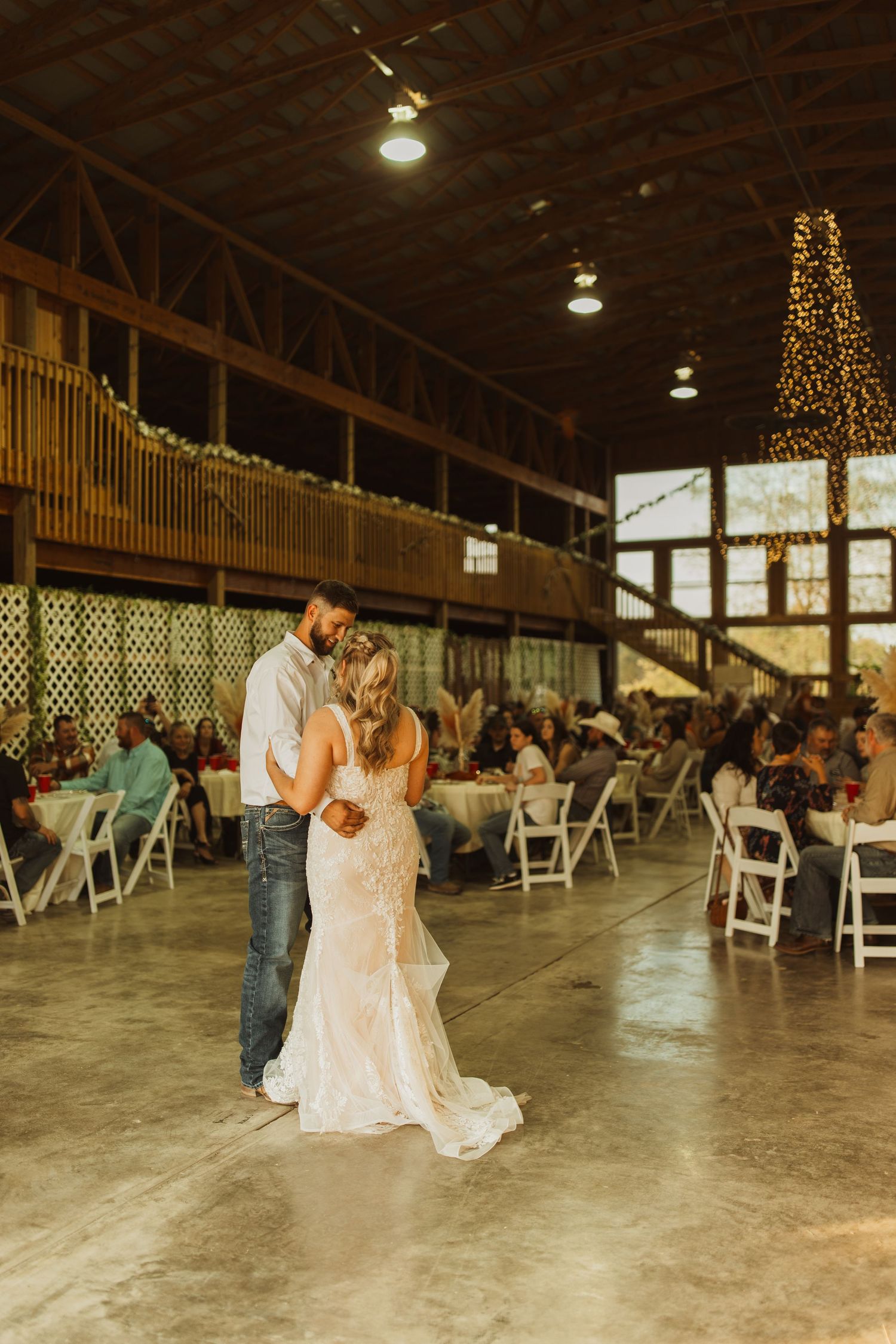 A romantic first dance at a rustic barn wedding reception with string lights and decorations.