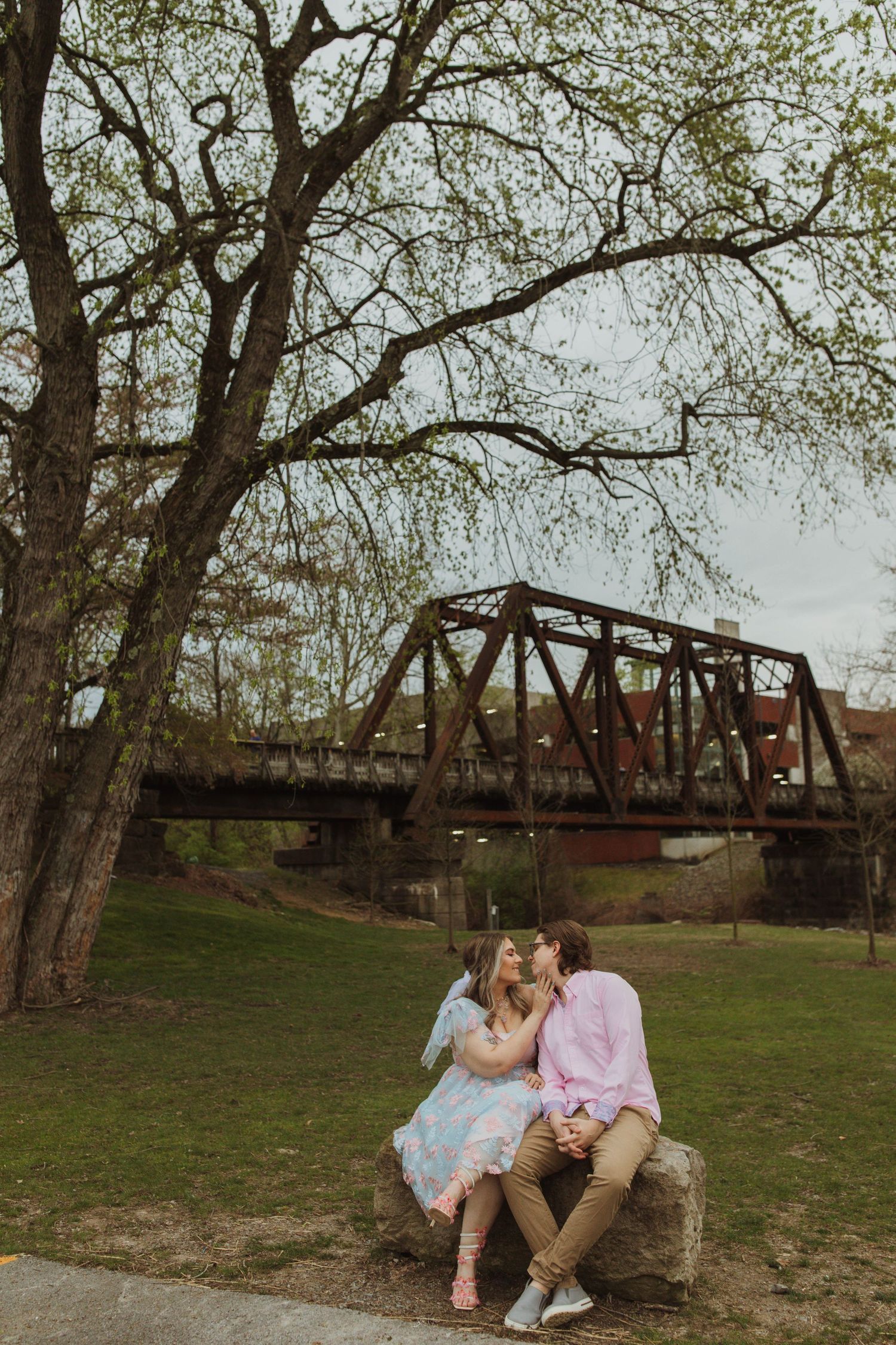Couple sitting on rock by old railway bridge during spring.