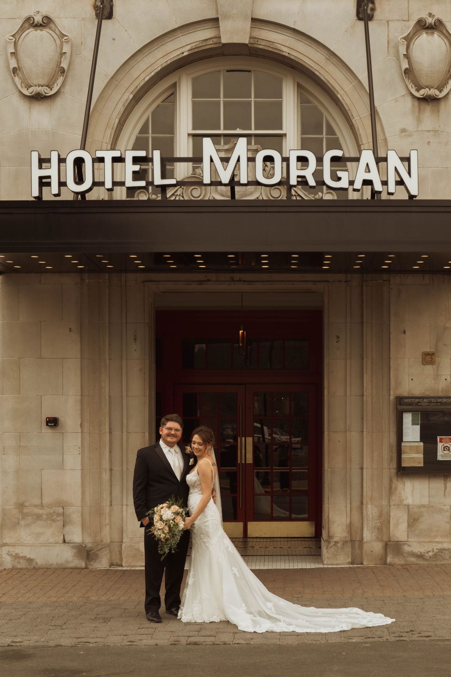 A wedding portrait featuring the historic Hotel Morgan facade and entrance in warm tones.