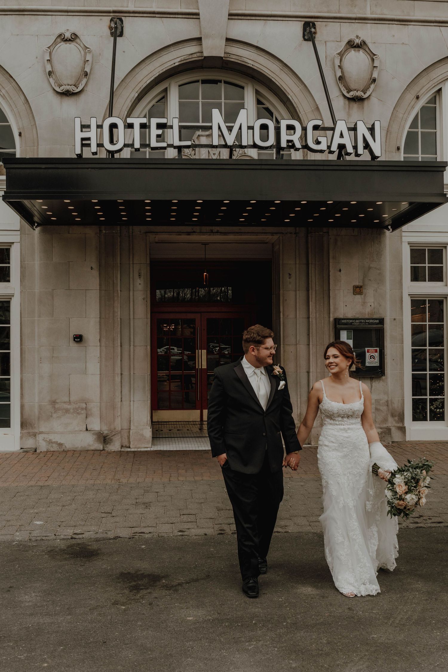 A couple walks together outside Hotel Morgan's entrance on their wedding day in vintage-style photography.