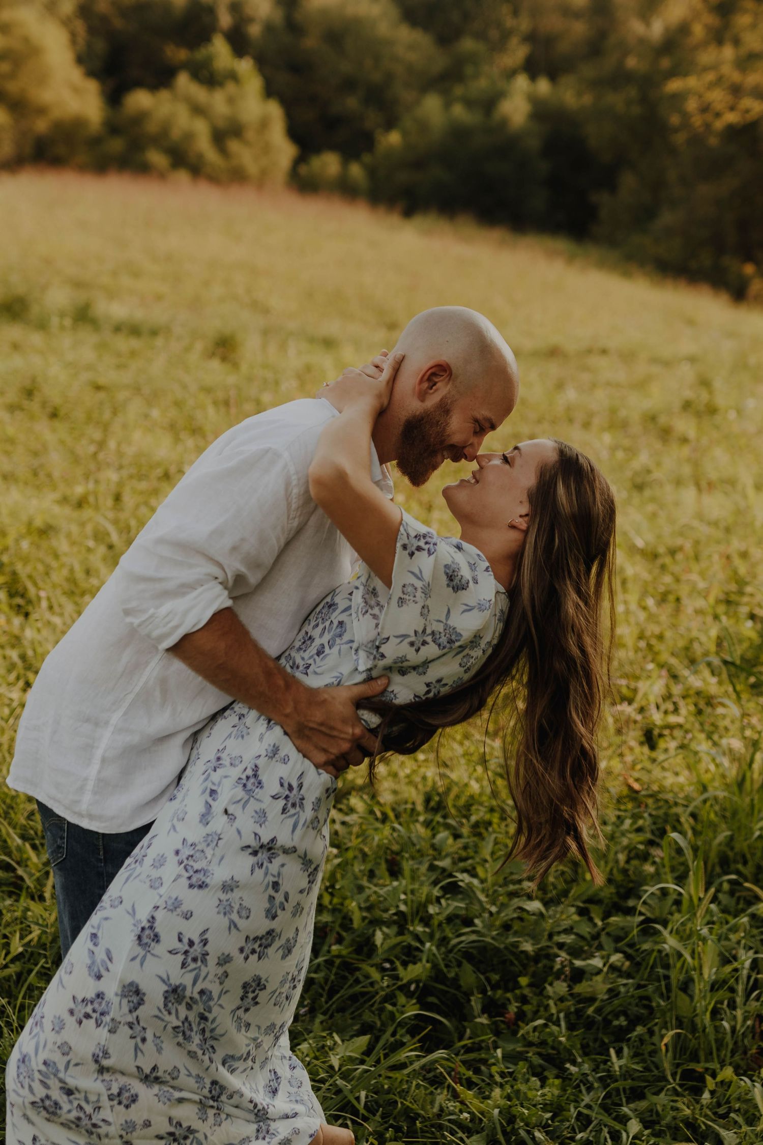 A romantic dip pose captured in a sun-drenched meadow during golden hour.