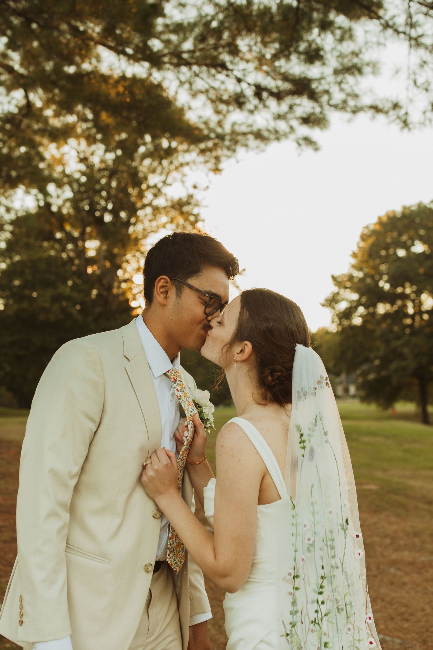 Couple shares intimate moment under trees during golden sunset.