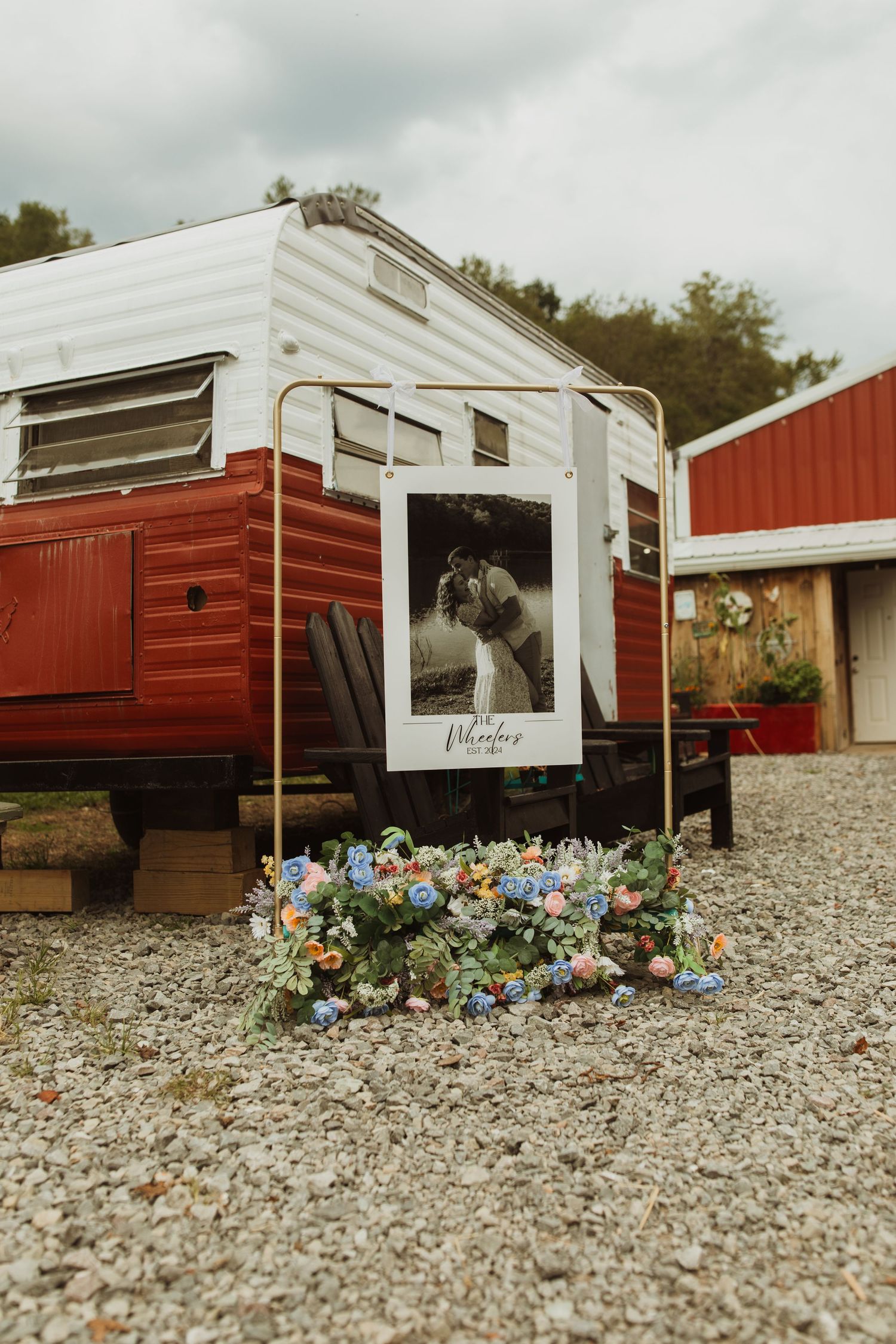 Vintage camper trailer with a large photo display and blue flowers decorating the entrance.