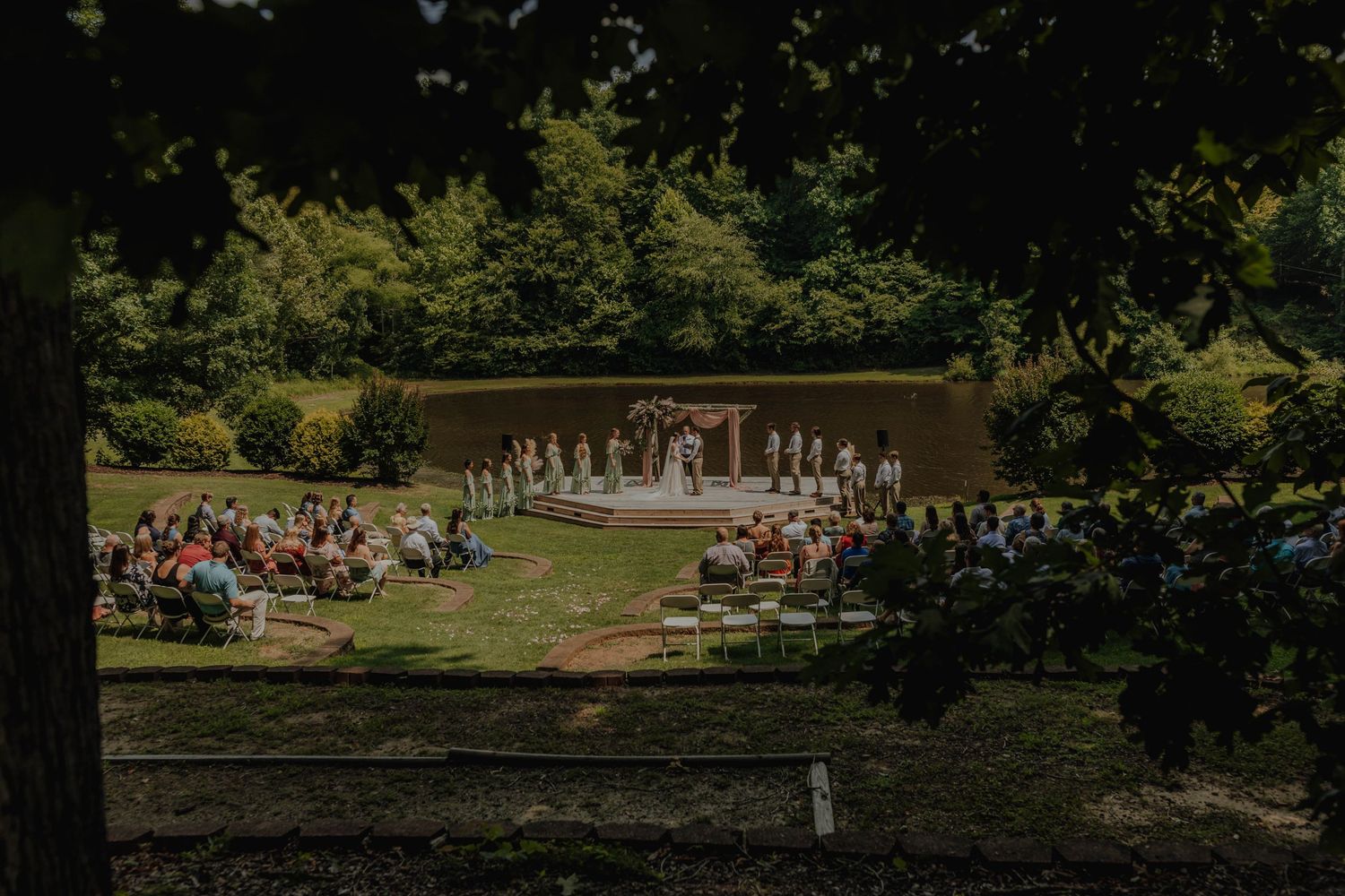 An outdoor wedding ceremony setup with white chairs and floral arrangements in a garden setting.