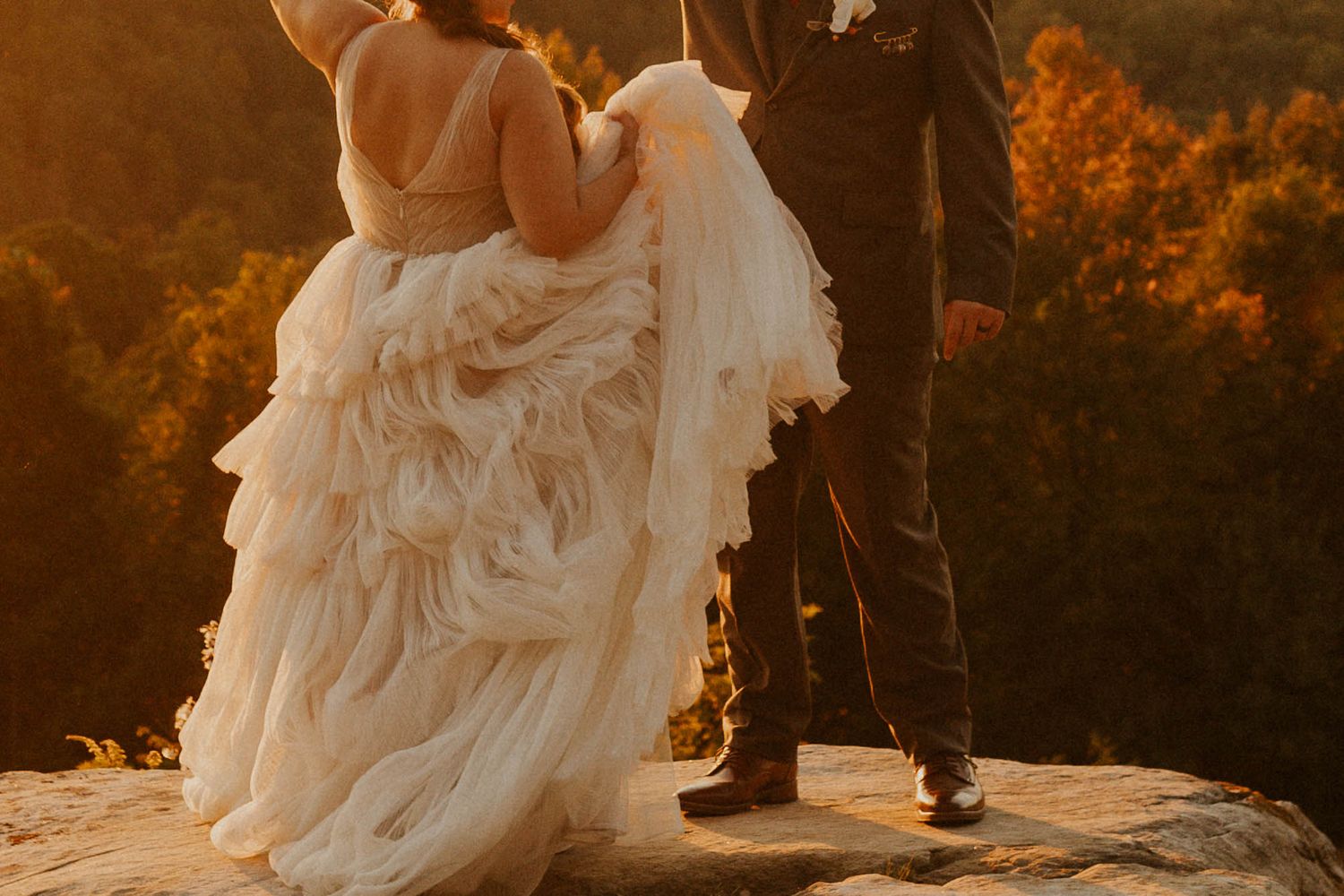 A close-up of a flowing white wedding dress with ruffled details during golden hour.