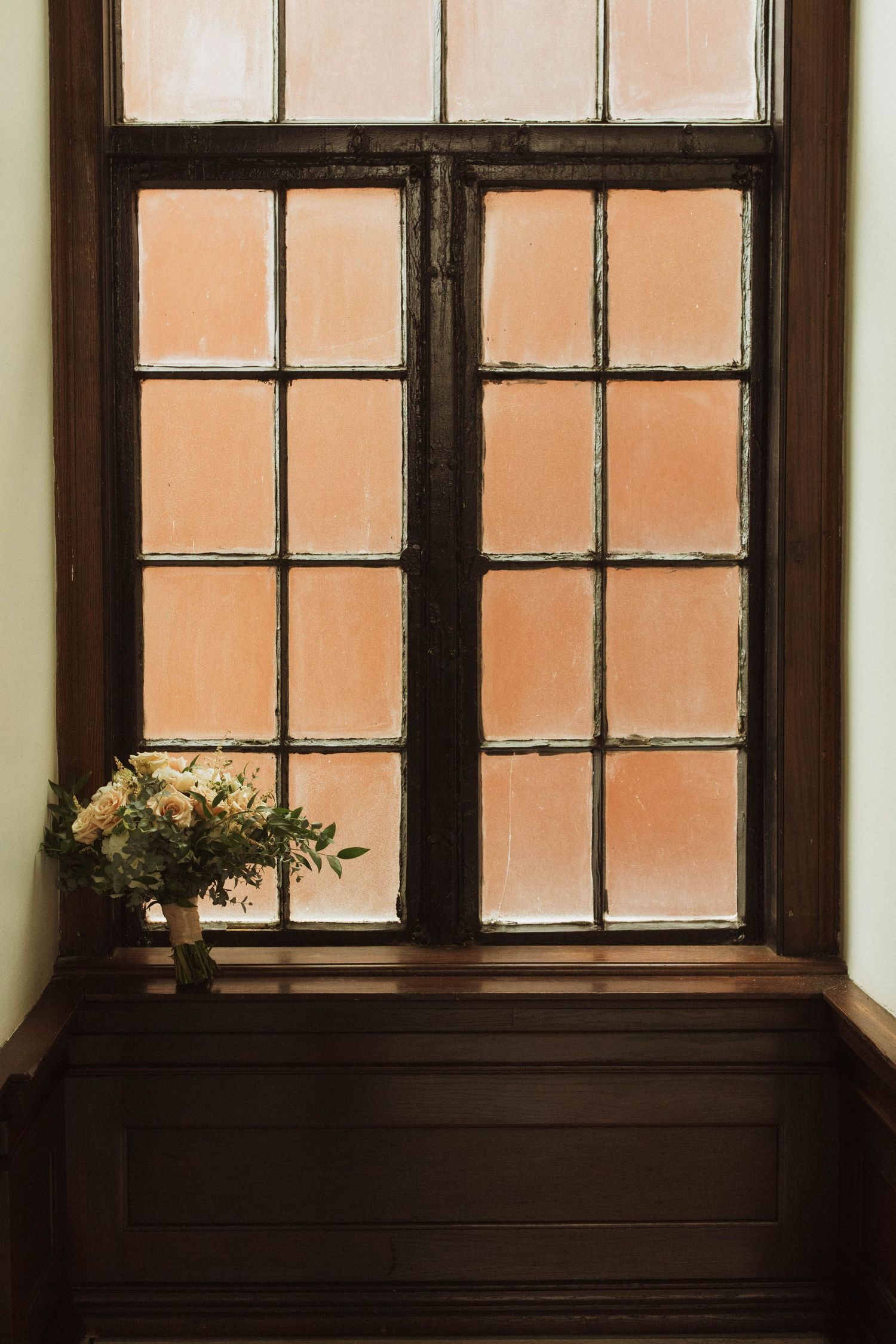 A minimalist window scene with wooden trim and small floral arrangement on the sill.