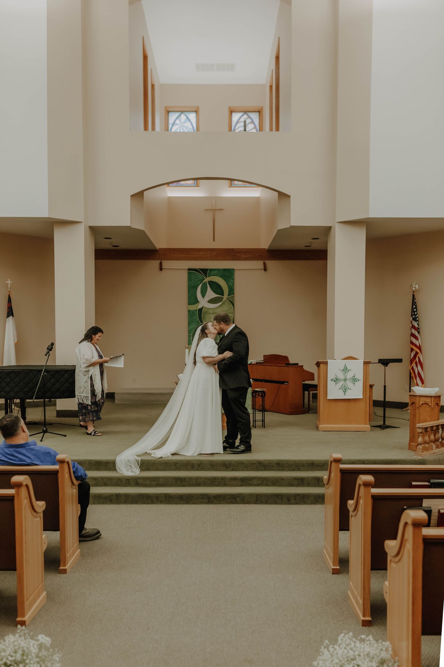 A church wedding ceremony with wooden pews and bright interior lighting.