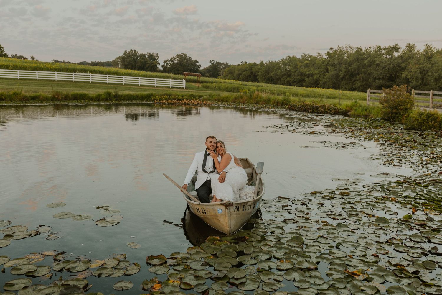 A romantic boat ride on a lily pad covered pond at sunset with rustic wooden oars.