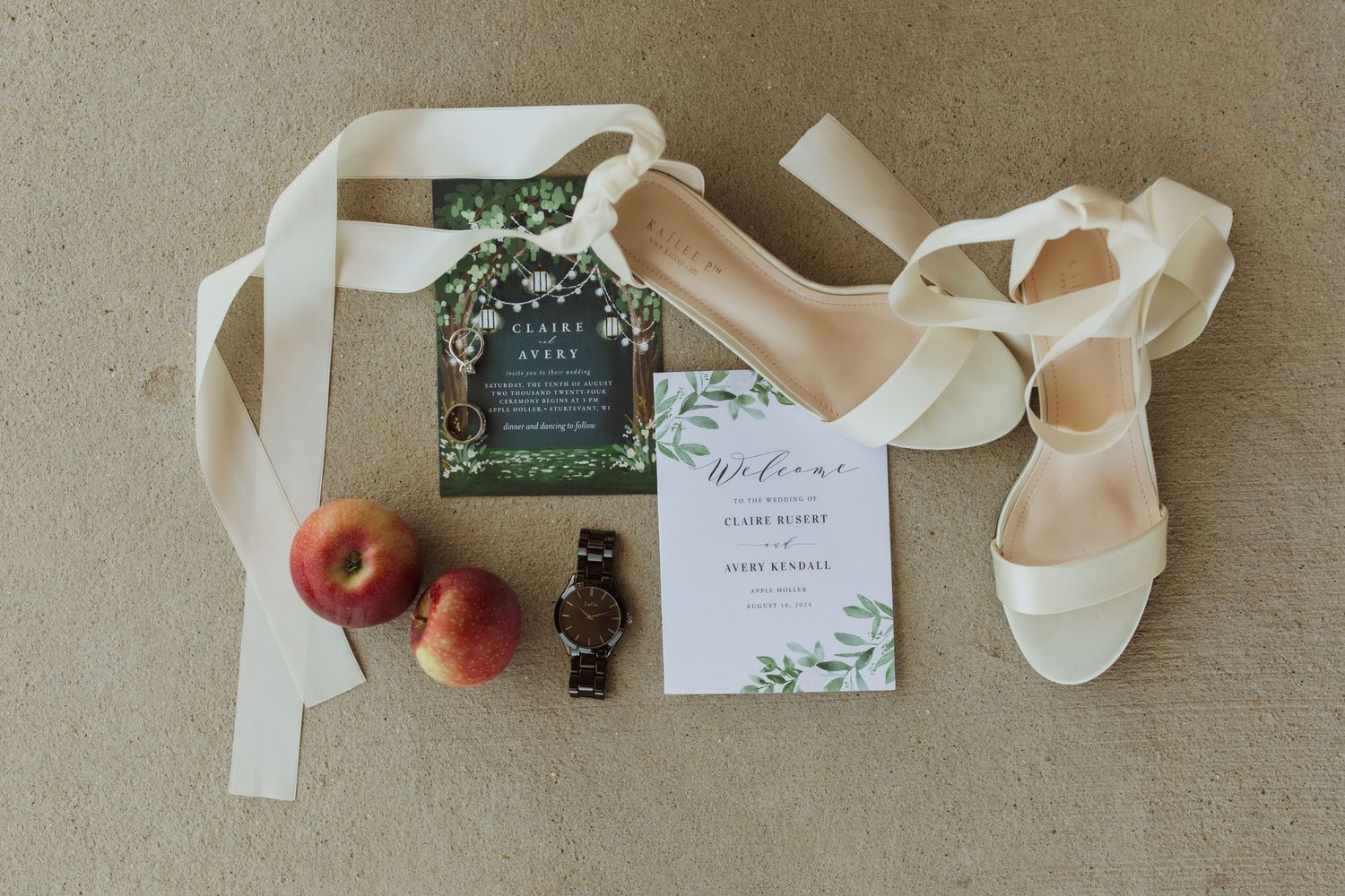 Wedding invitation suite with white shoes, fresh apples and elegant stationery on beige background.