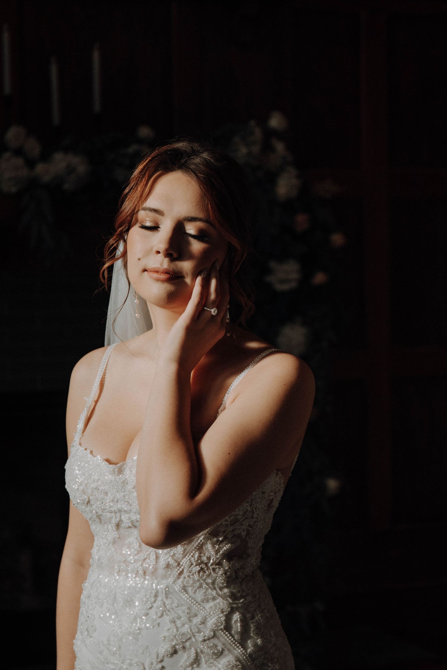 Moody portrait of bride in lace dress with dramatic lighting.