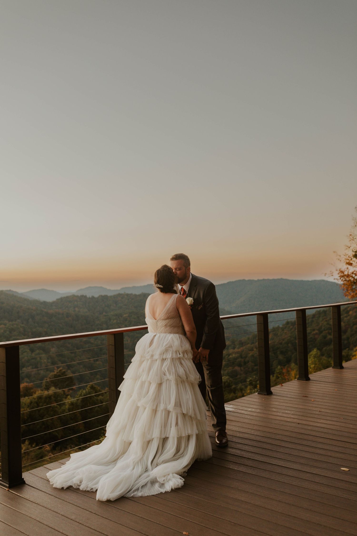 Romantic sunset wedding photo on a mountain deck with panoramic views.