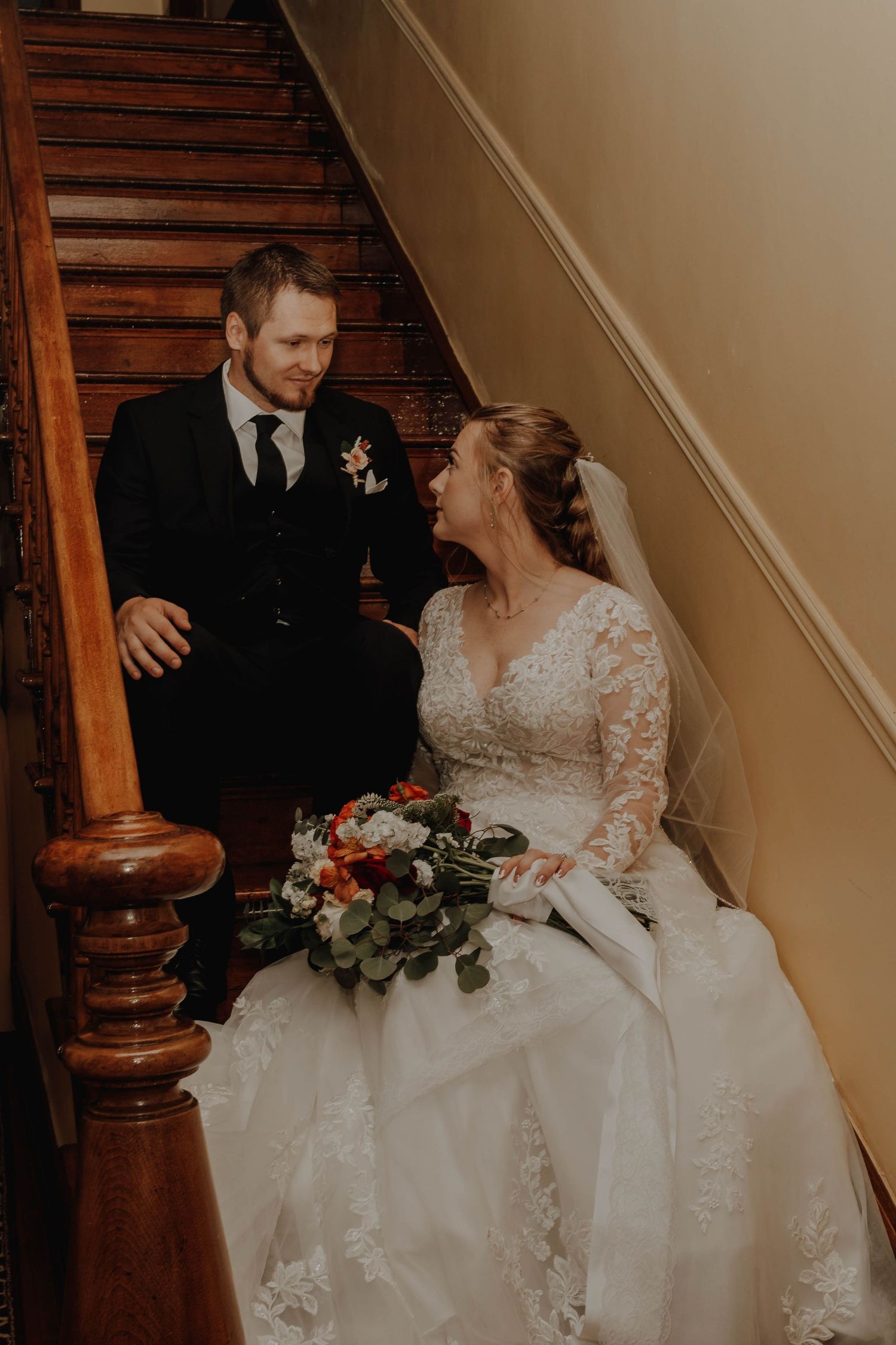 A tender moment between newlyweds on vintage wooden stairs.