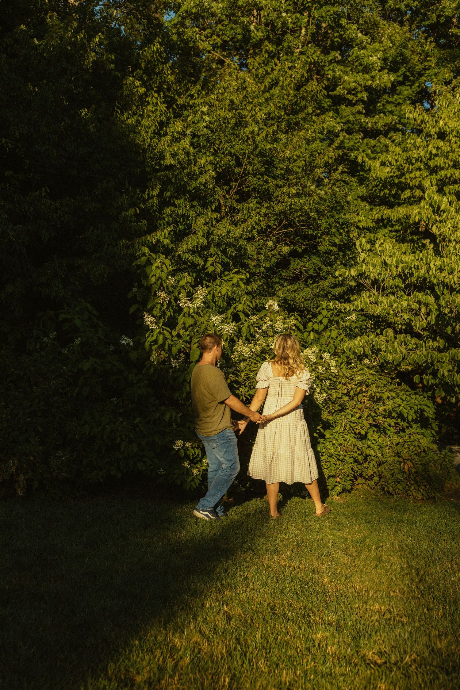 Couple dancing on a grassy lawn during golden hour.