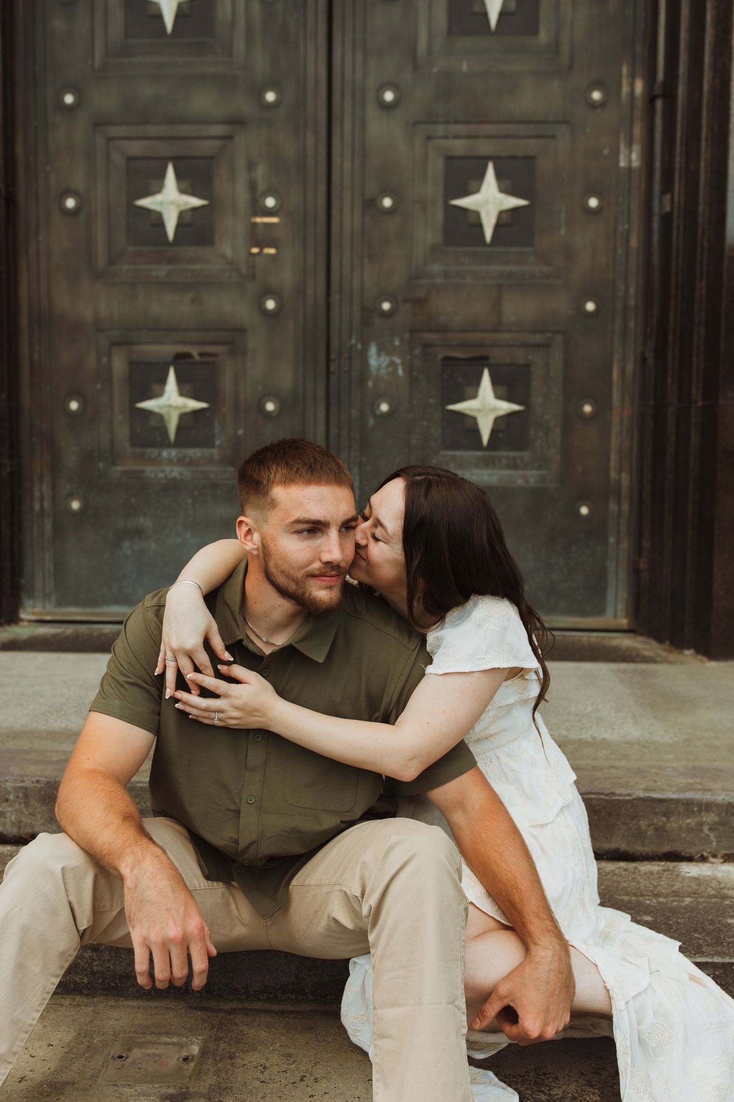 An intimate moment shared on stone steps in front of an ornate door with star patterns.