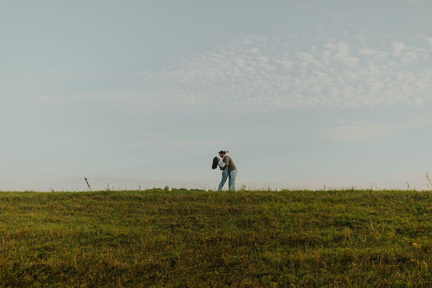 Person taking photos on a hilltop during sunset with camera equipment.
