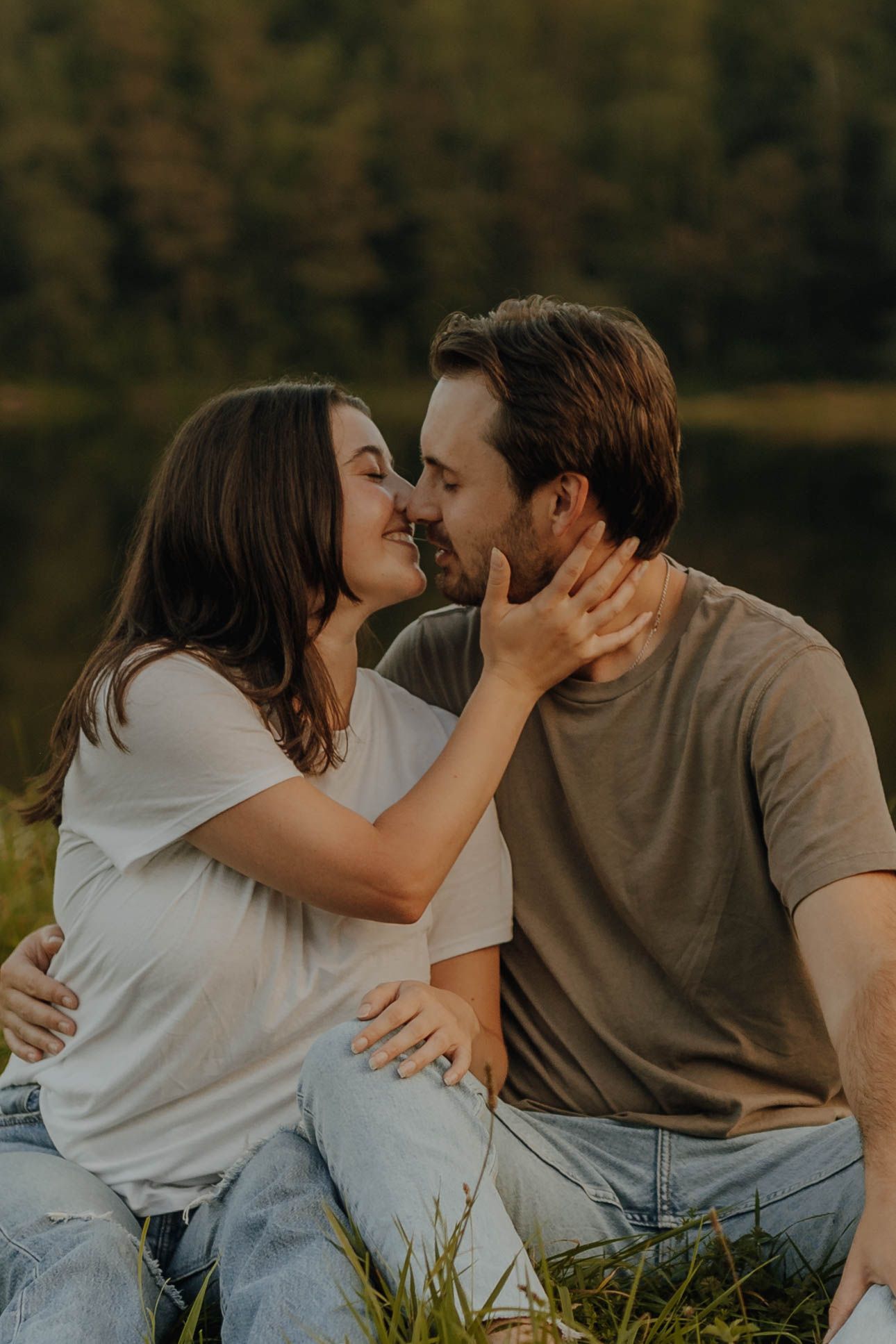 Intimate moment between a couple sitting in grass during sunset.