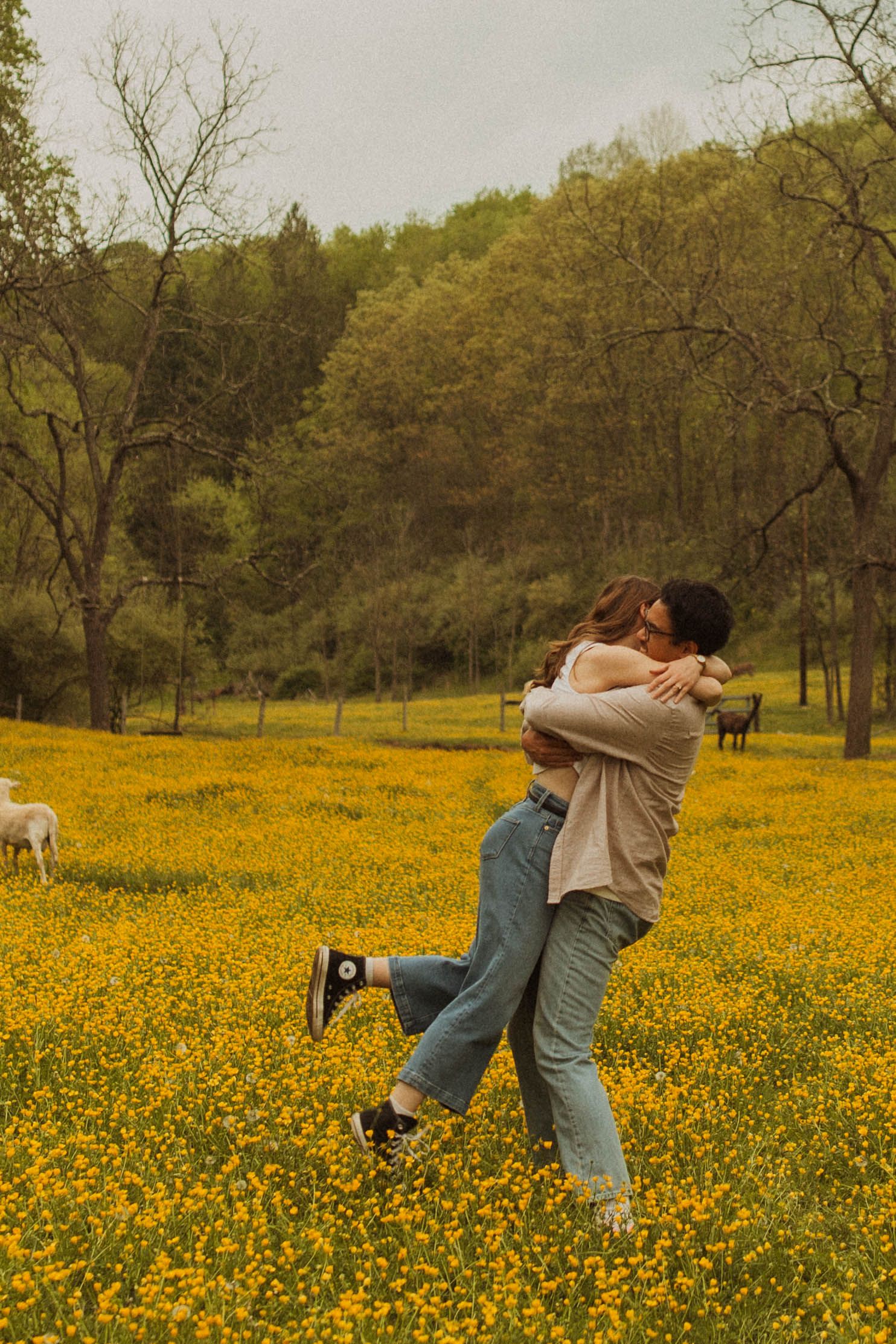 A couple embraces joyfully in a field of yellow wildflowers.