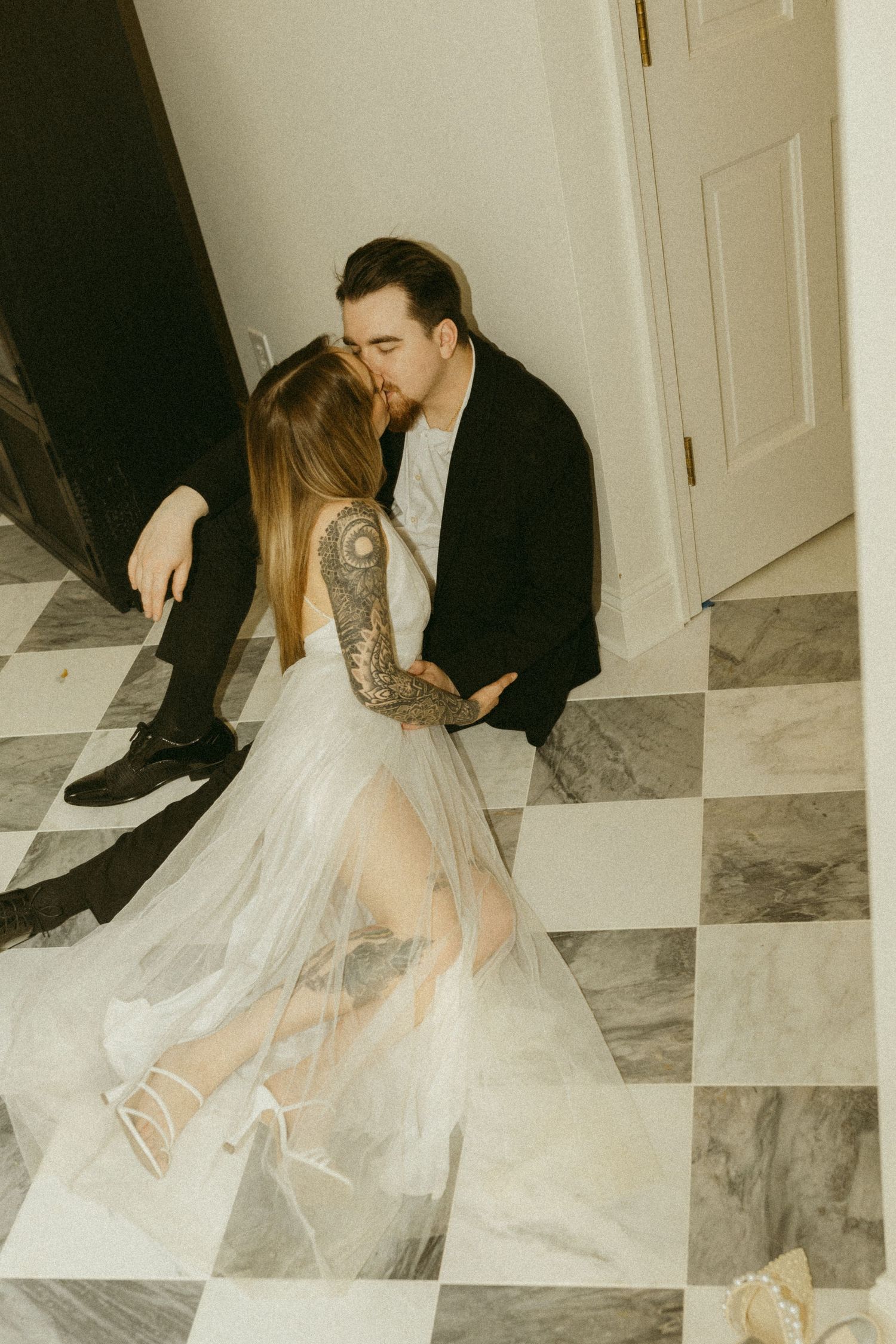 An intimate moment between newlyweds on a checkered marble floor.