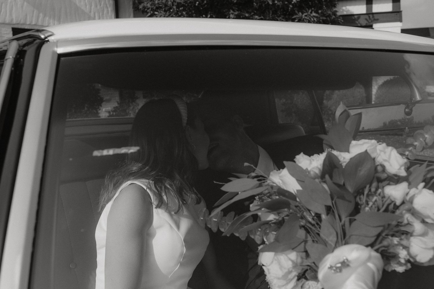 A monochrome interior car shot with wedding flowers visible through the window.