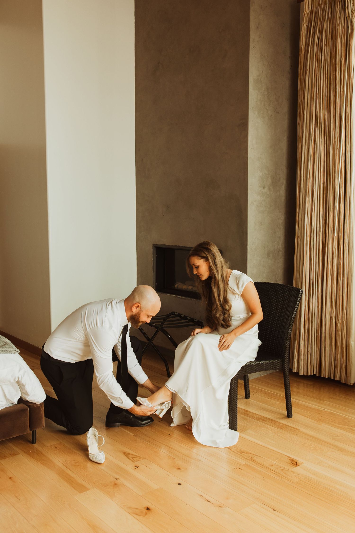 Wedding preparation moment as shoes are adjusted in a modern hotel room.