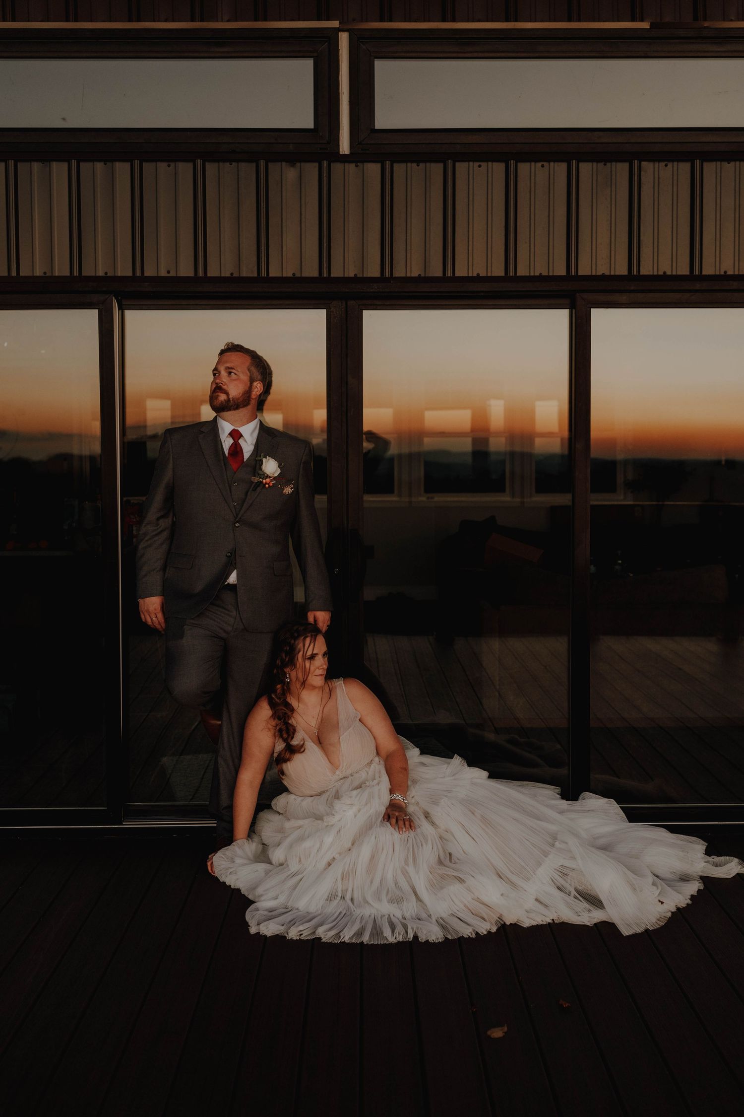 Dramatic wedding portrait with couple against modern architecture at dusk.