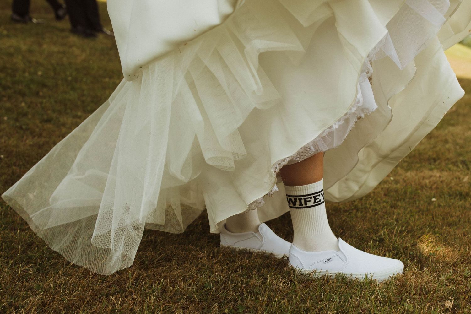 Detail shot of bridal shoes and layered tulle dress hem on grass.