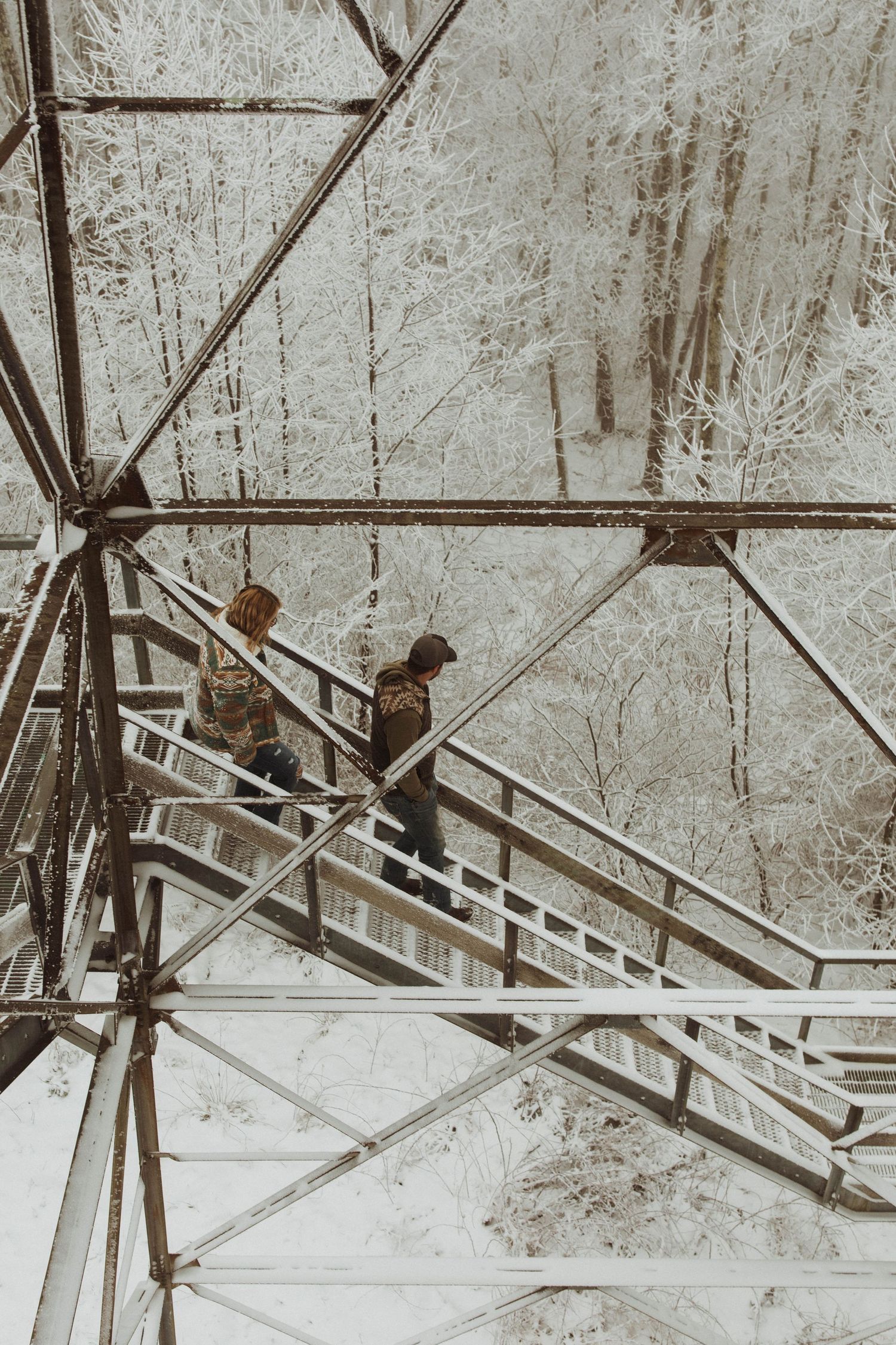 Two figures descend steel stairs of an industrial structure in a vintage sepia photograph.