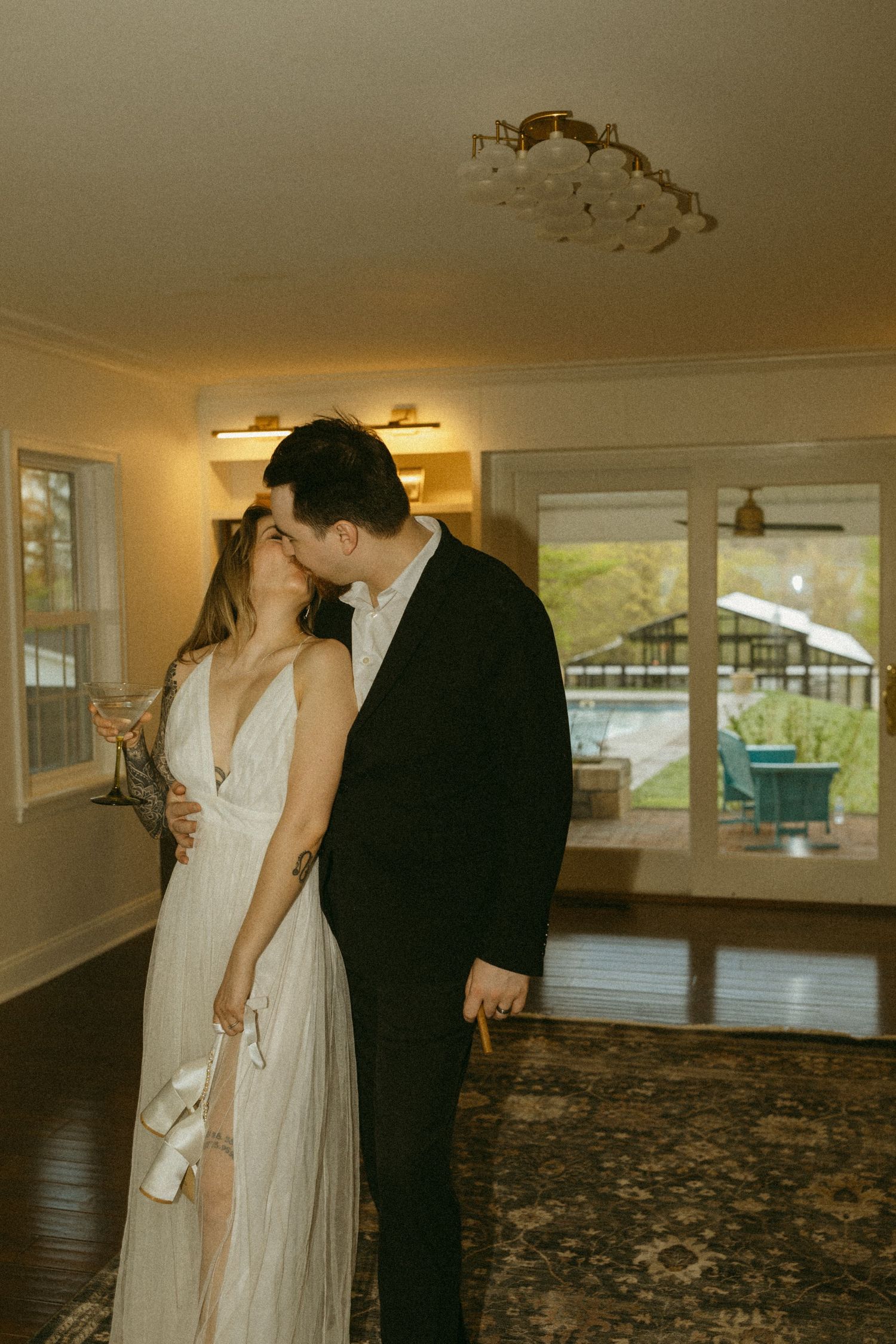Romantic wedding photo with couple kissing in sunlit room.