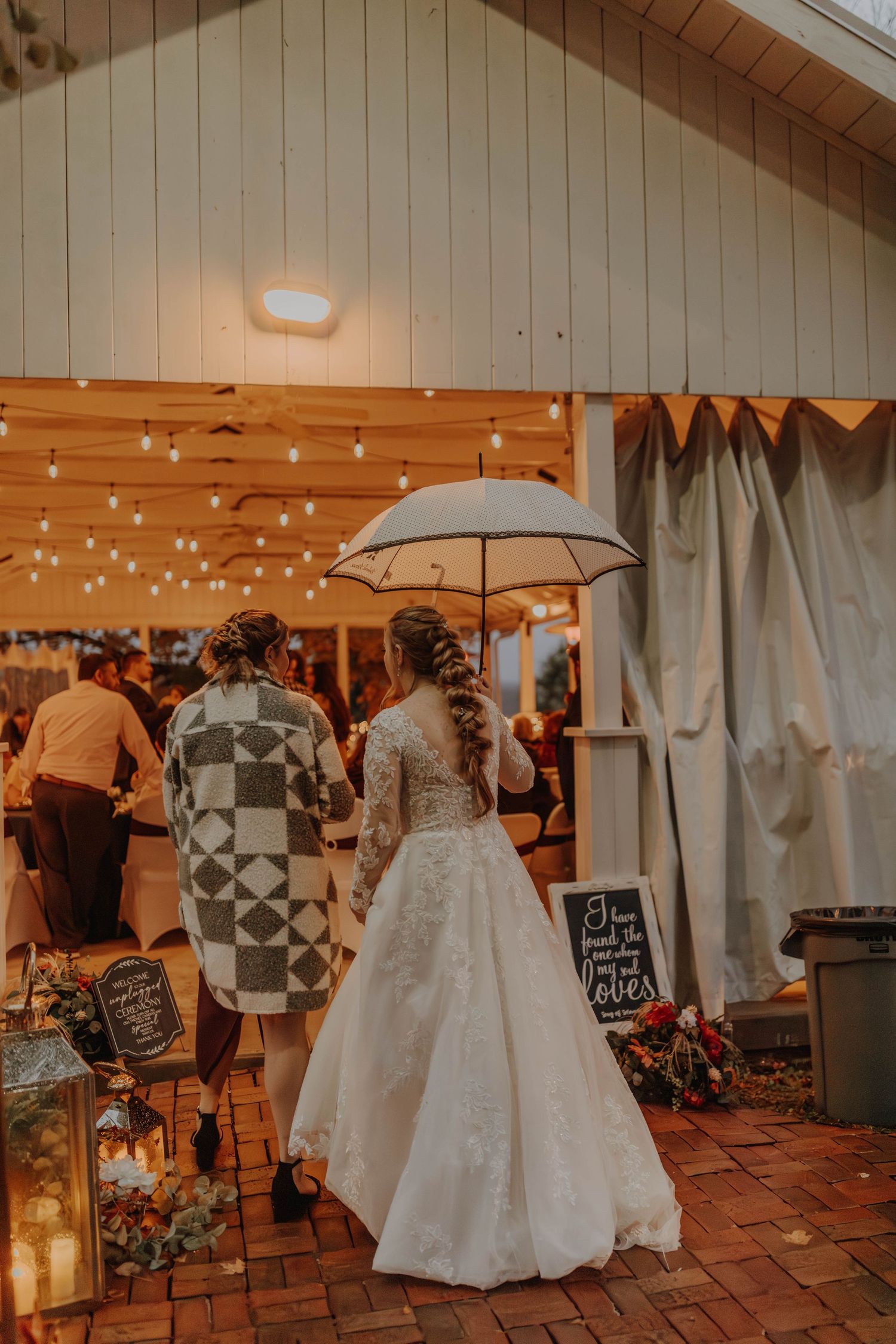 A wedding reception scene with string lights and an umbrella decoration.