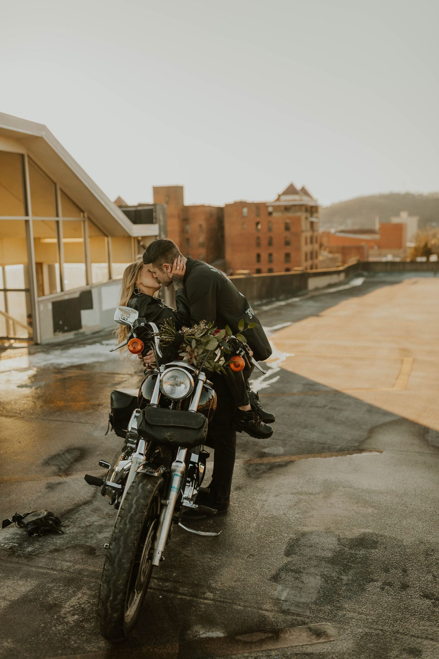 A motorcycle is parked on a rooftop with urban buildings visible in the warm evening light.