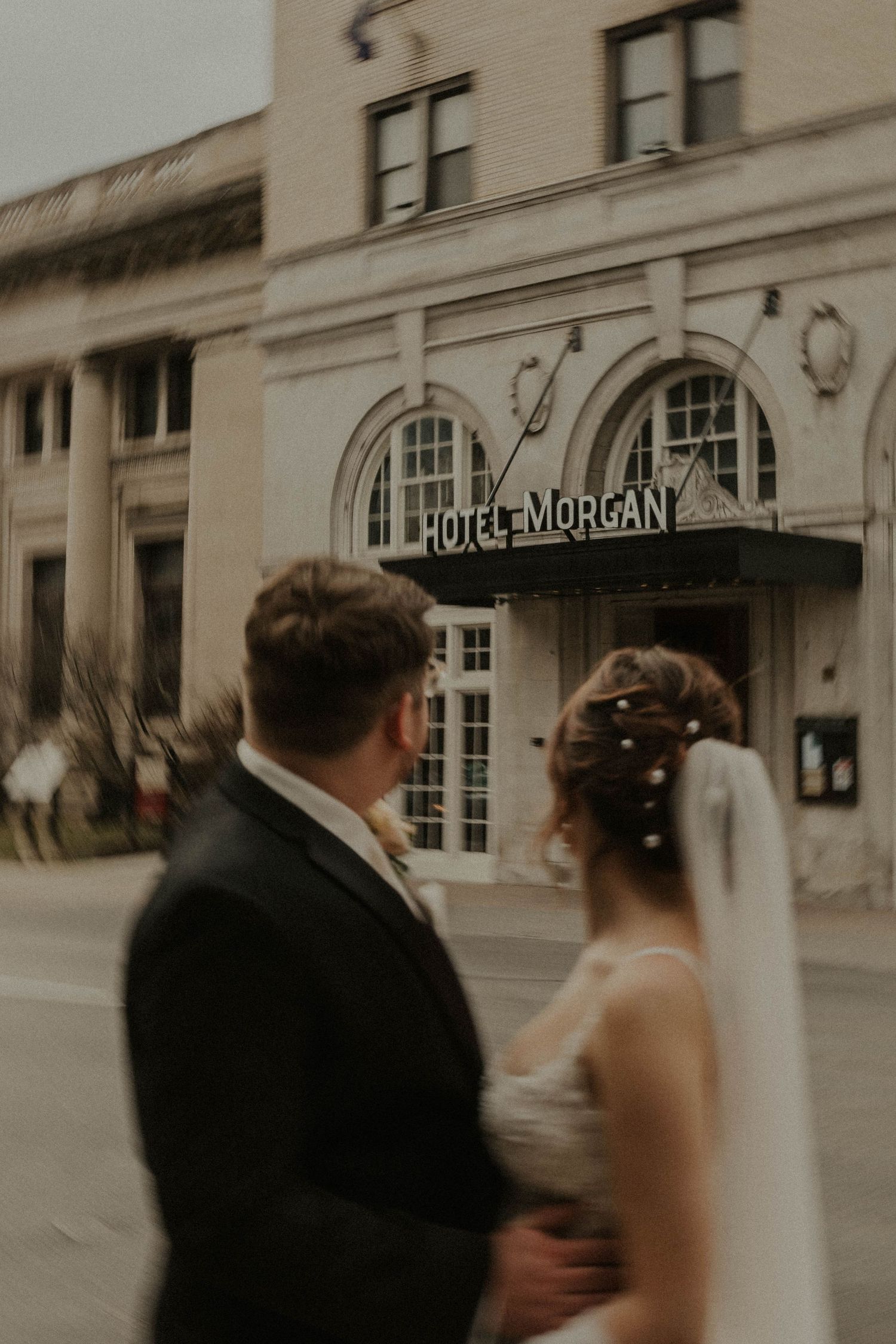A sepia-toned intimate moment between newlyweds at the Hotel Morgan entrance.