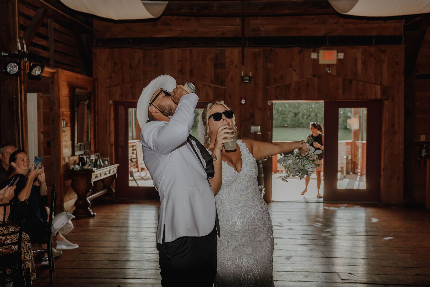 Wedding guests dancing in a rustic wooden barn venue with string lights.