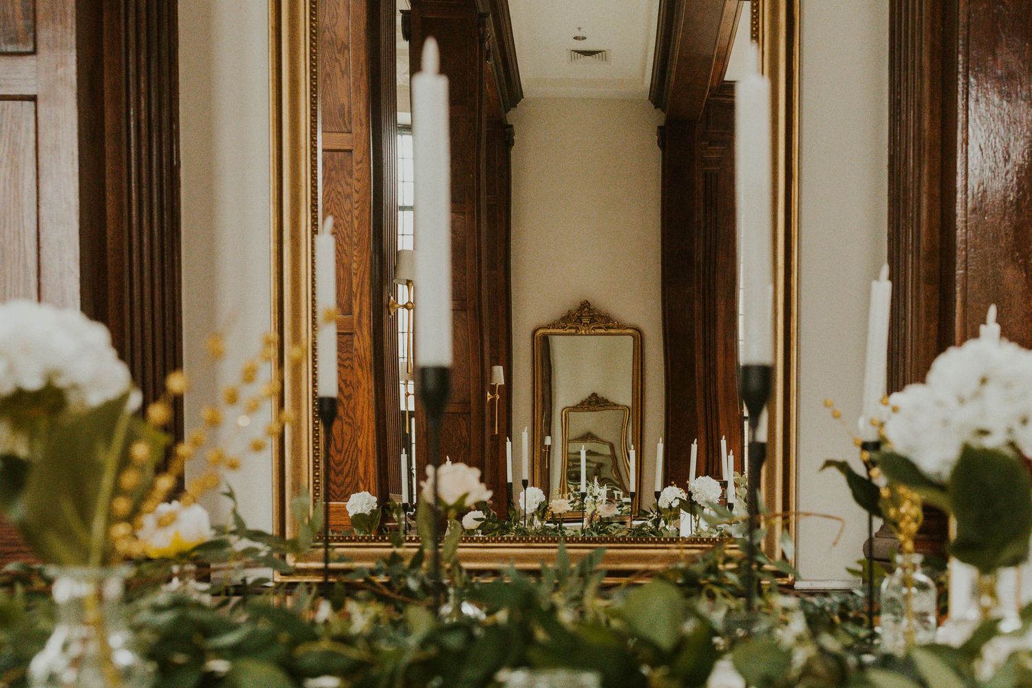 Ornate mirror display with white floral arrangements in an elegant hallway.