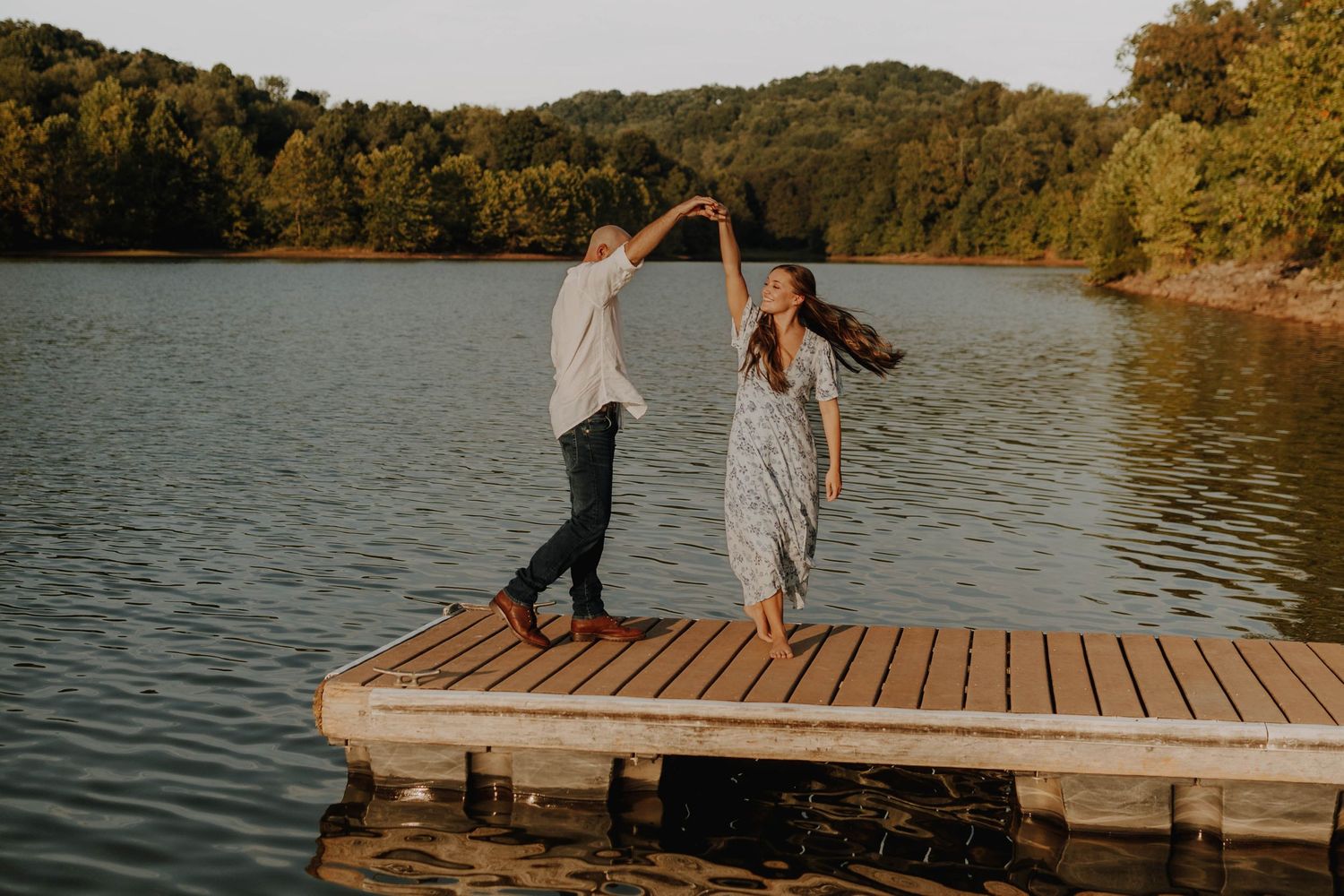 A playful moment shared on a wooden dock overlooking a serene lake at sunset.