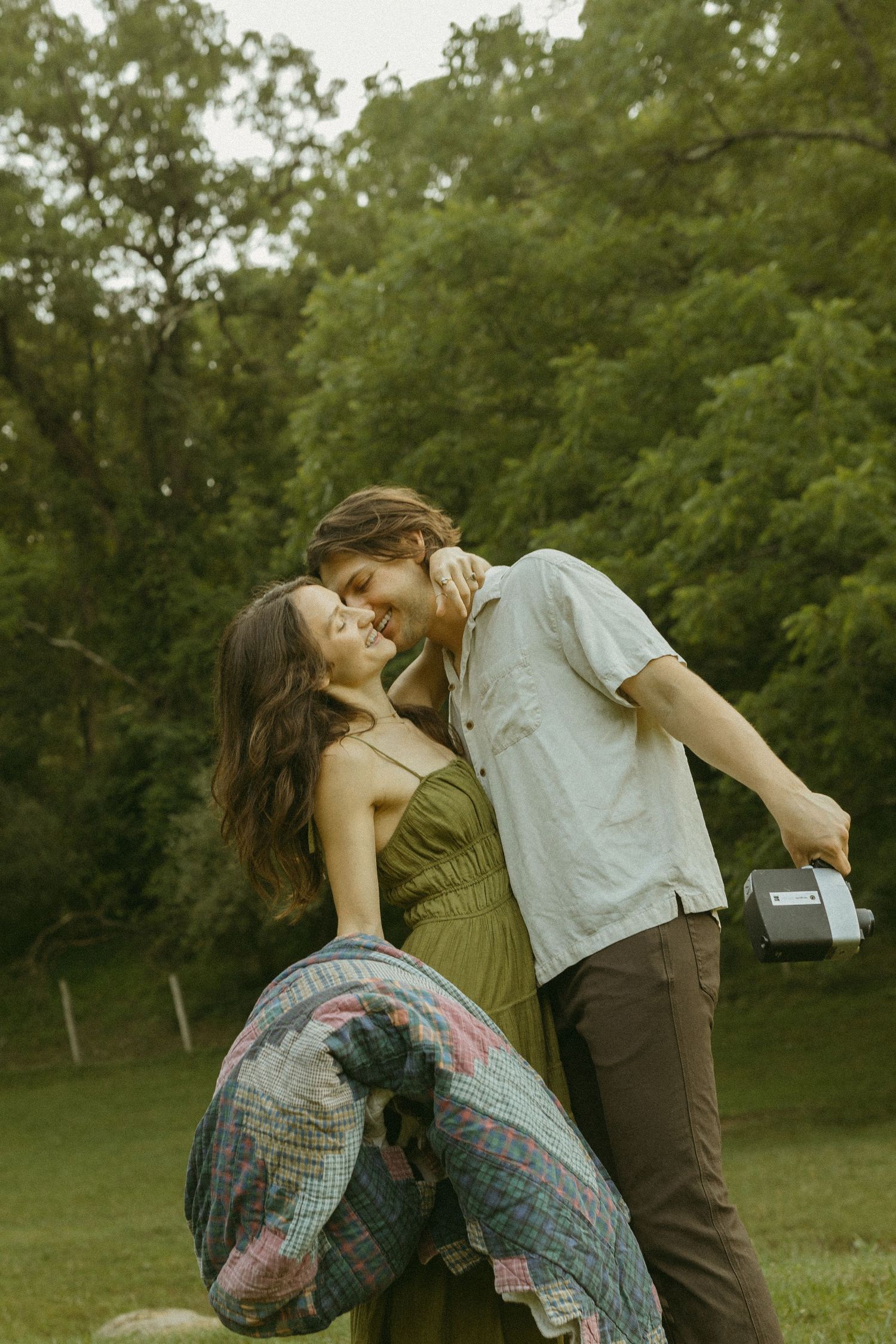 A romantic moment captured during a casual picnic in a green park setting.