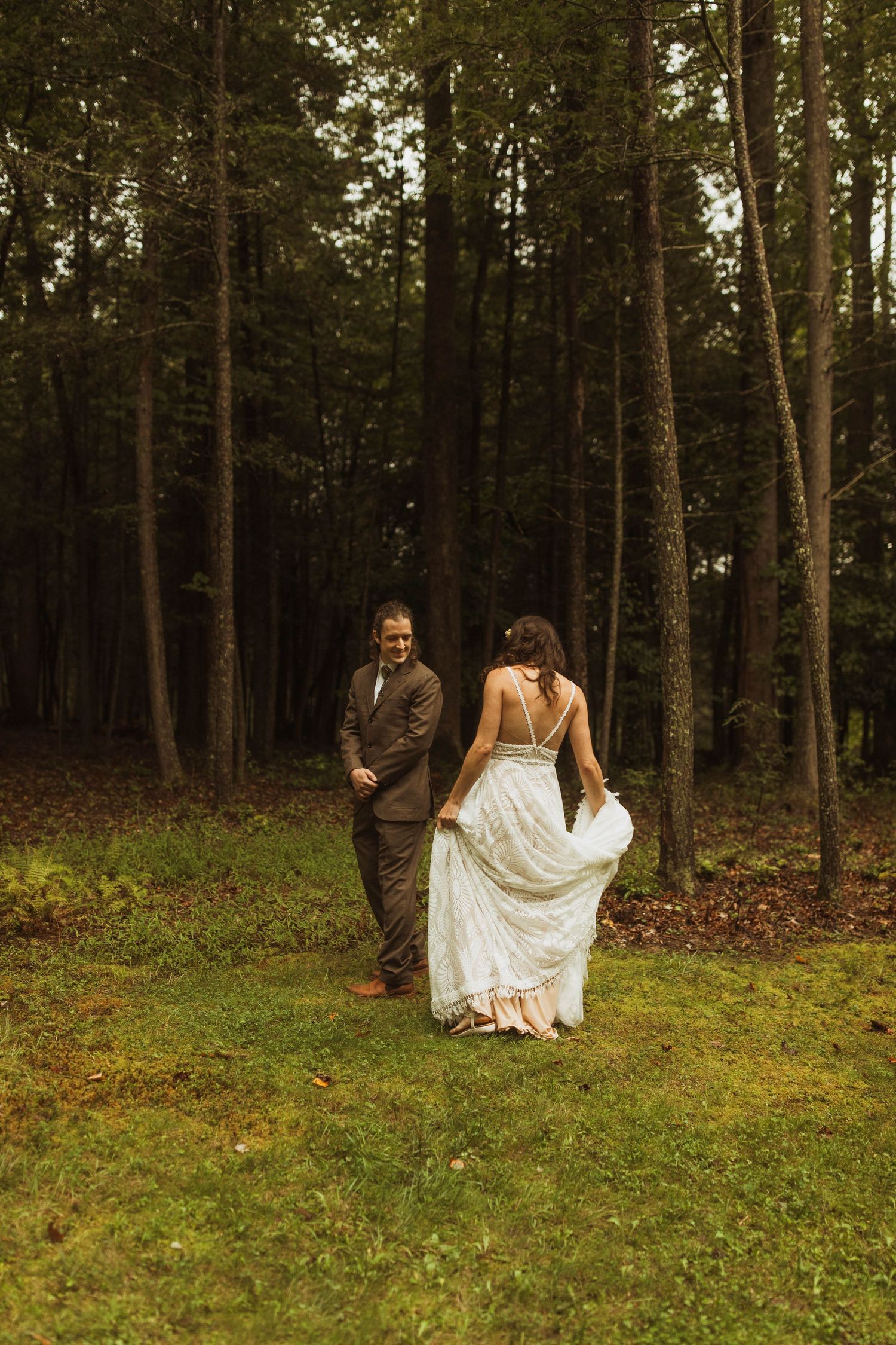 A couple walking through a forest clearing with the bride's dress flowing in the breeze.