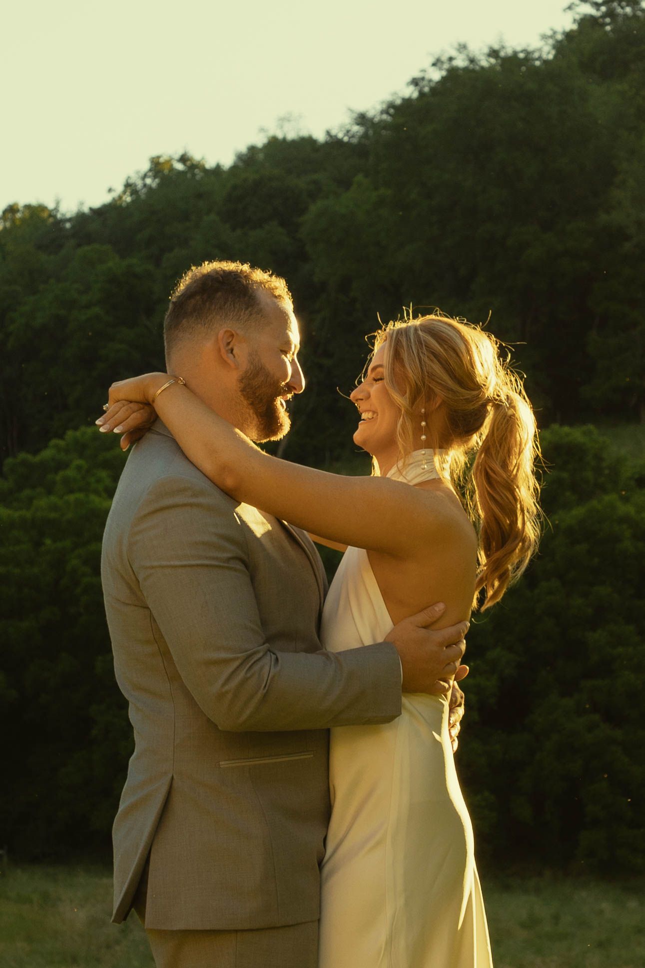 Wedding couple embraces during golden hour in a romantic outdoor setting.