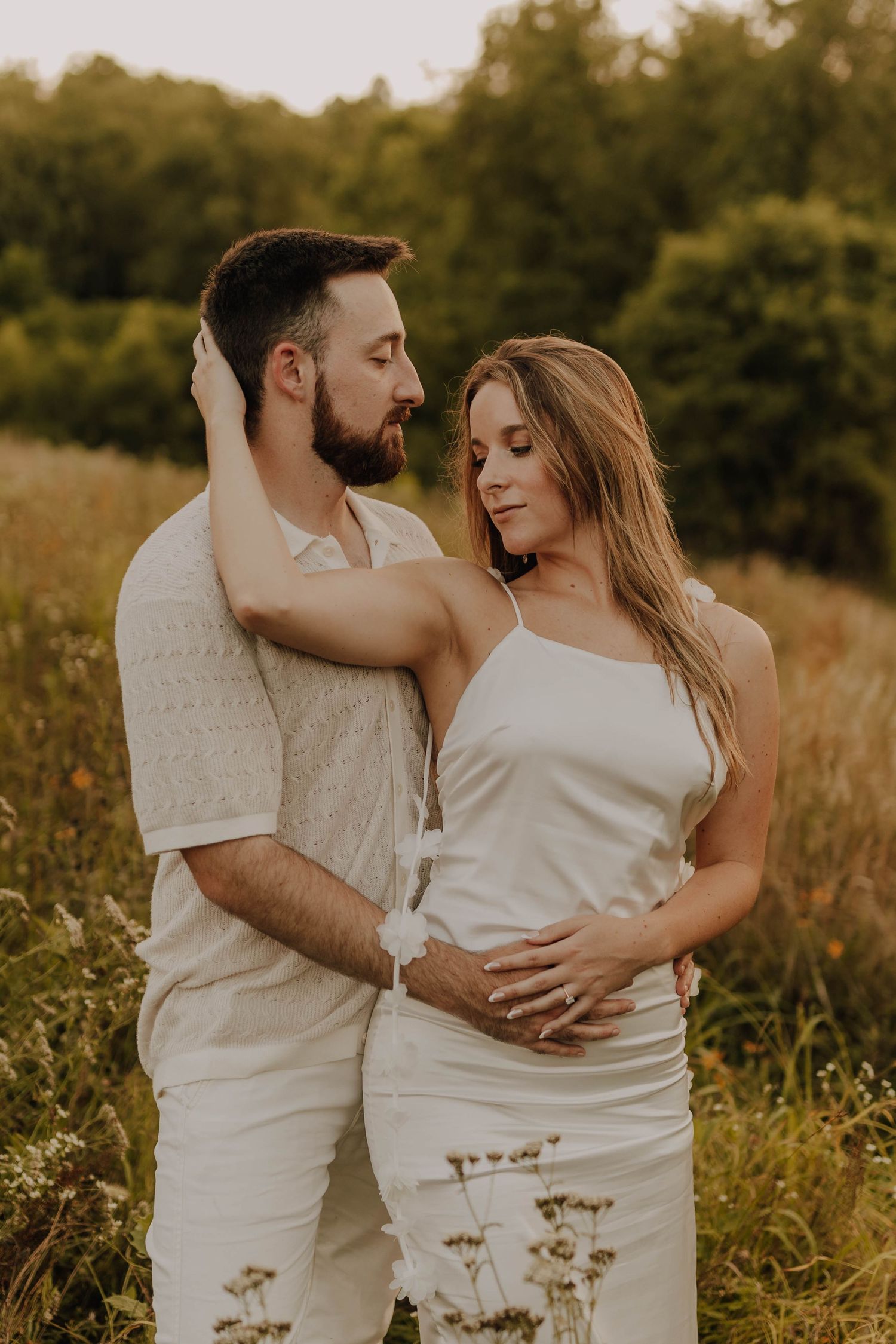 A romantic portrait in a sunlit meadow with golden wildflowers and natural scenery.