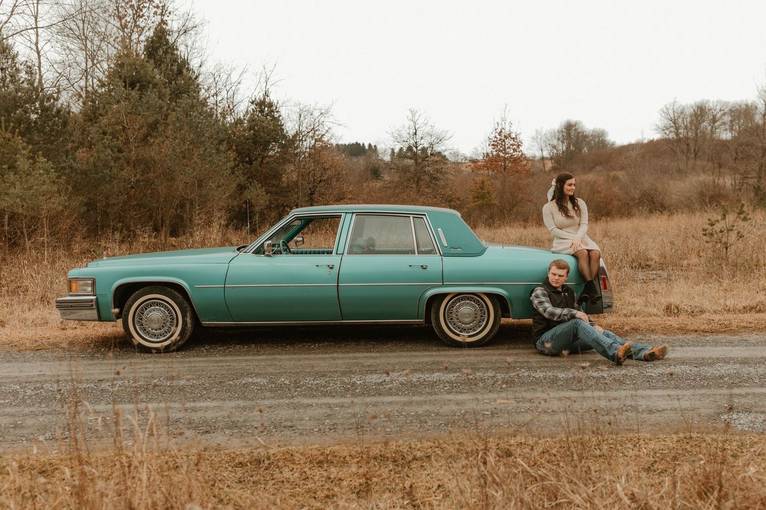 A mint green vintage Cadillac sedan parked in an autumn field.