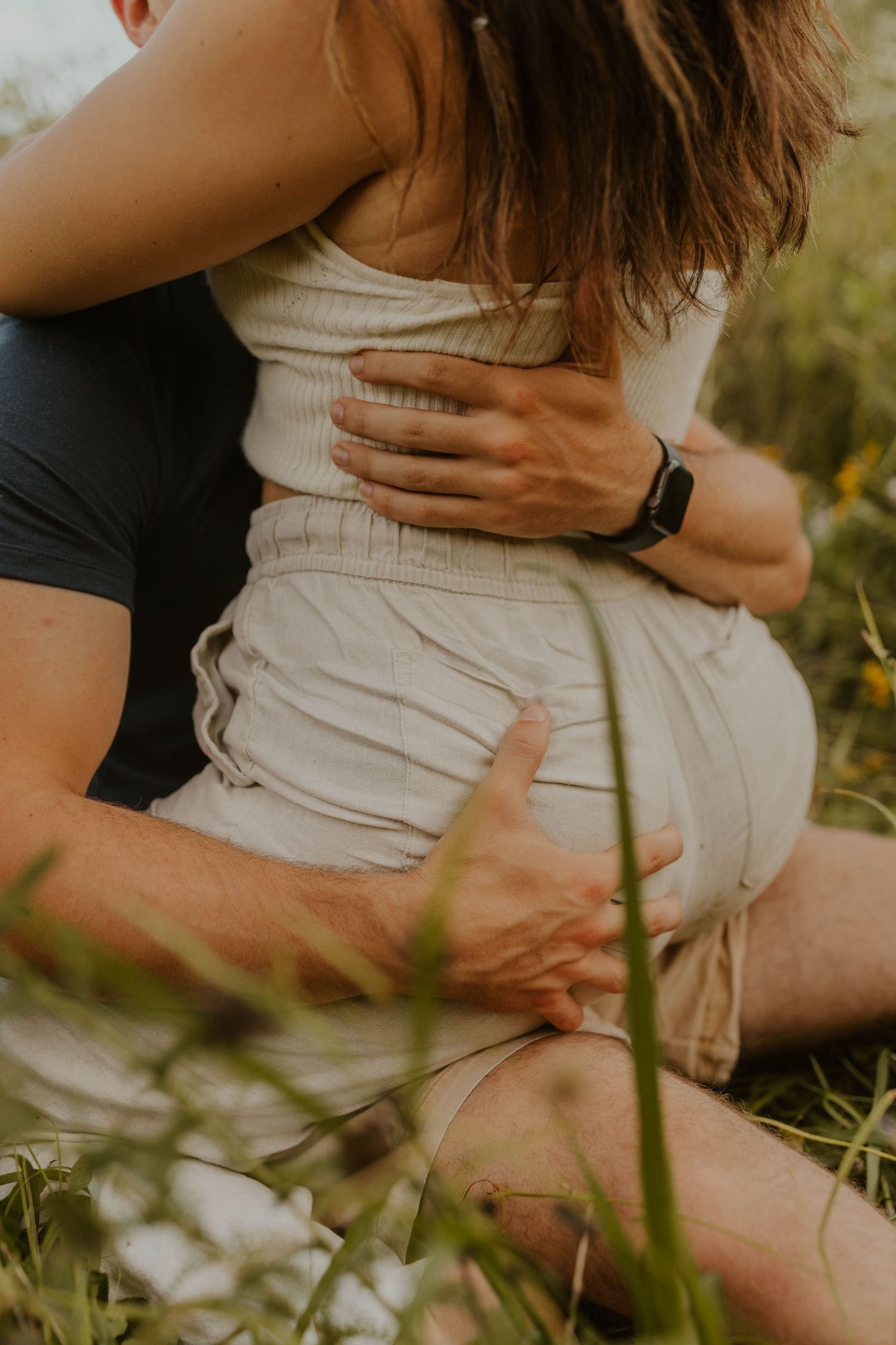 Close-up of an intimate embrace showing details of white dress and smart watch.
