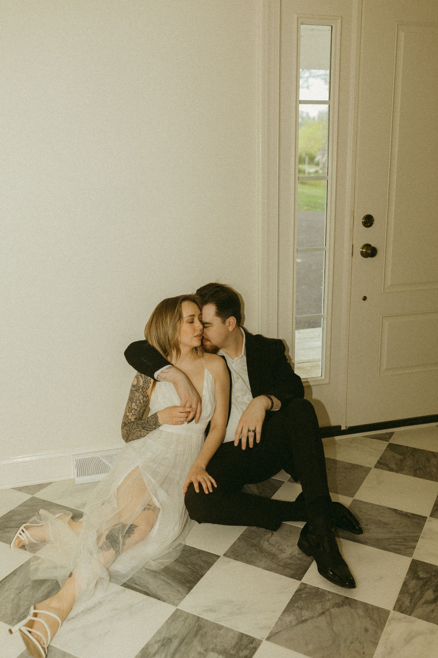 Vintage-style photo of couple in formal wear on black and white tiled floor.