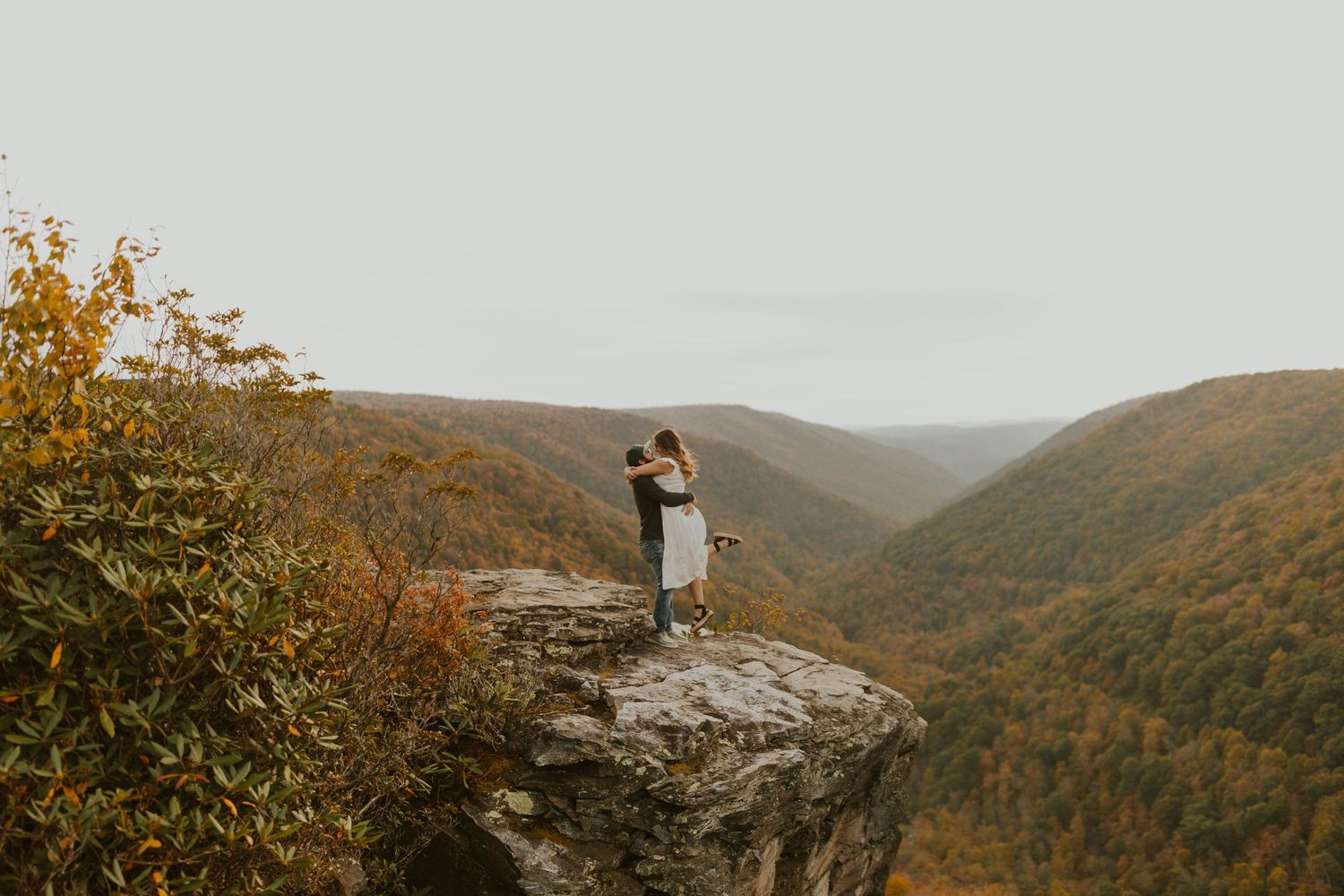 A romantic moment captured on a cliff edge overlooking a valley of fall colors at lindy point in blackwater falls state park