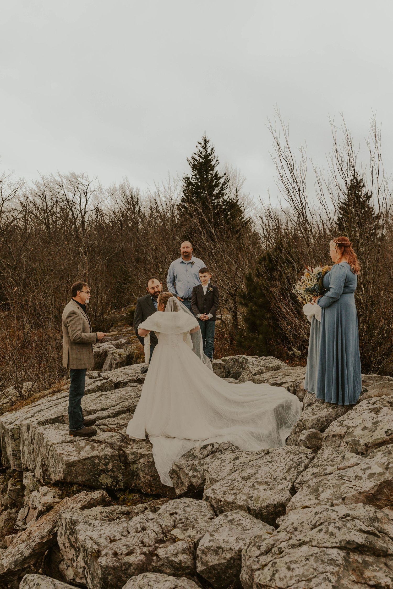Intimate wedding ceremony on rocky terrain with small group gathering.