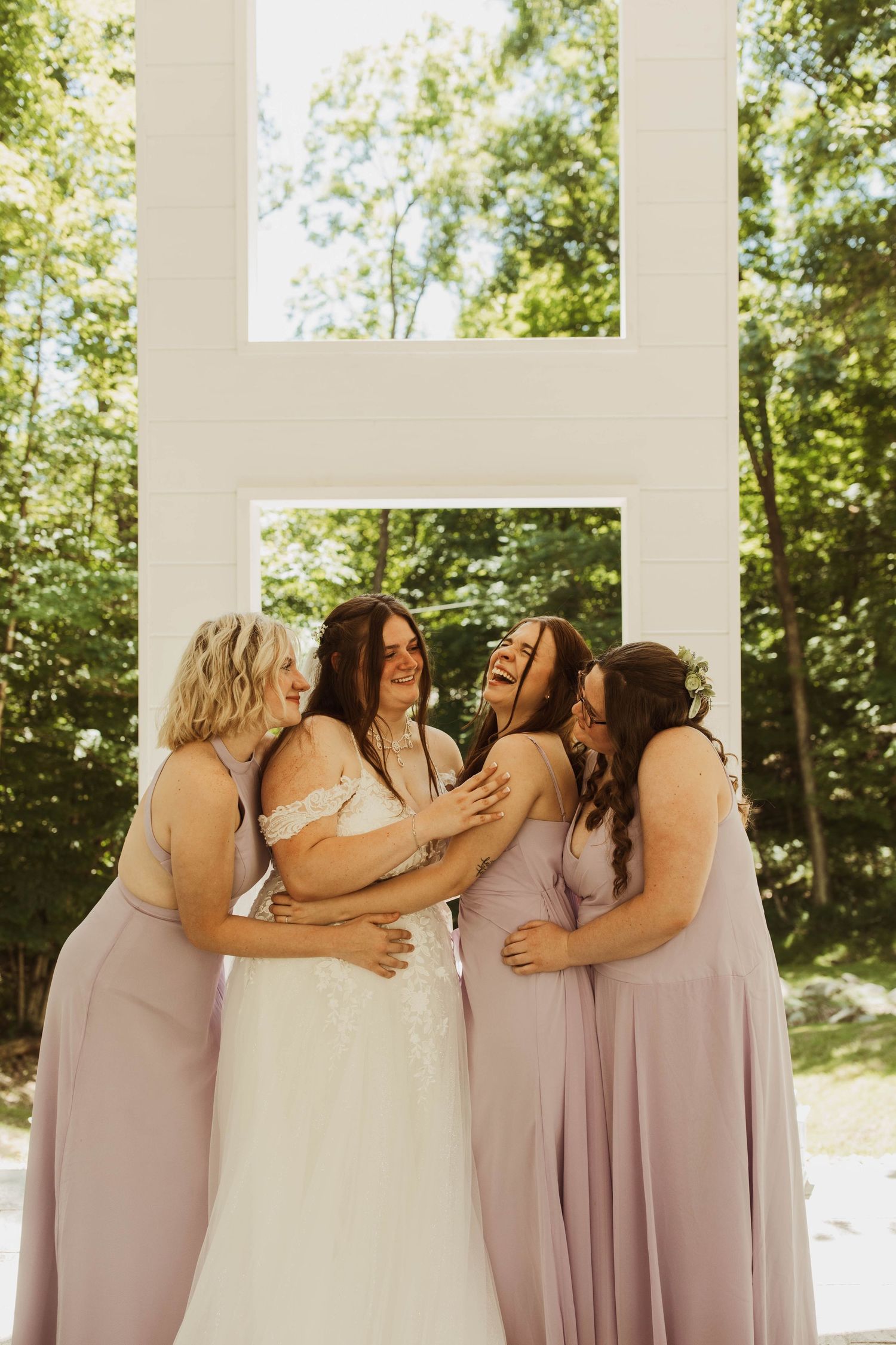 Joyful wedding party sharing an intimate moment together under bright natural lighting.