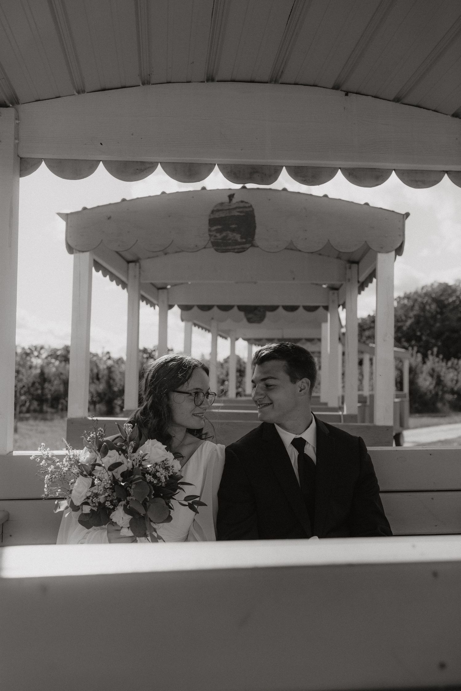 Black and white photo of a couple sitting in a white covered pavilion.