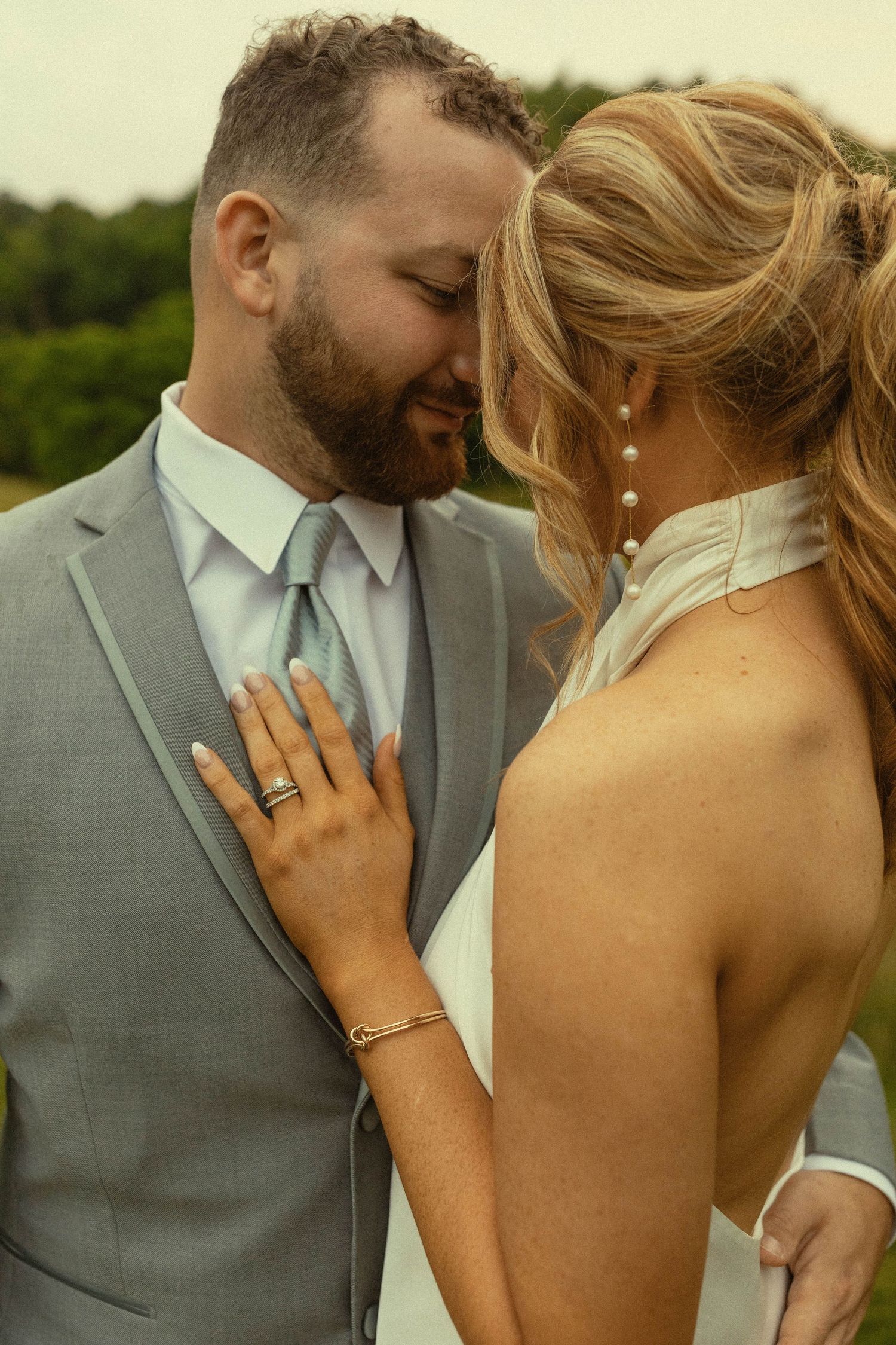 Intimate close-up of couple sharing tender moment outdoors during wedding.