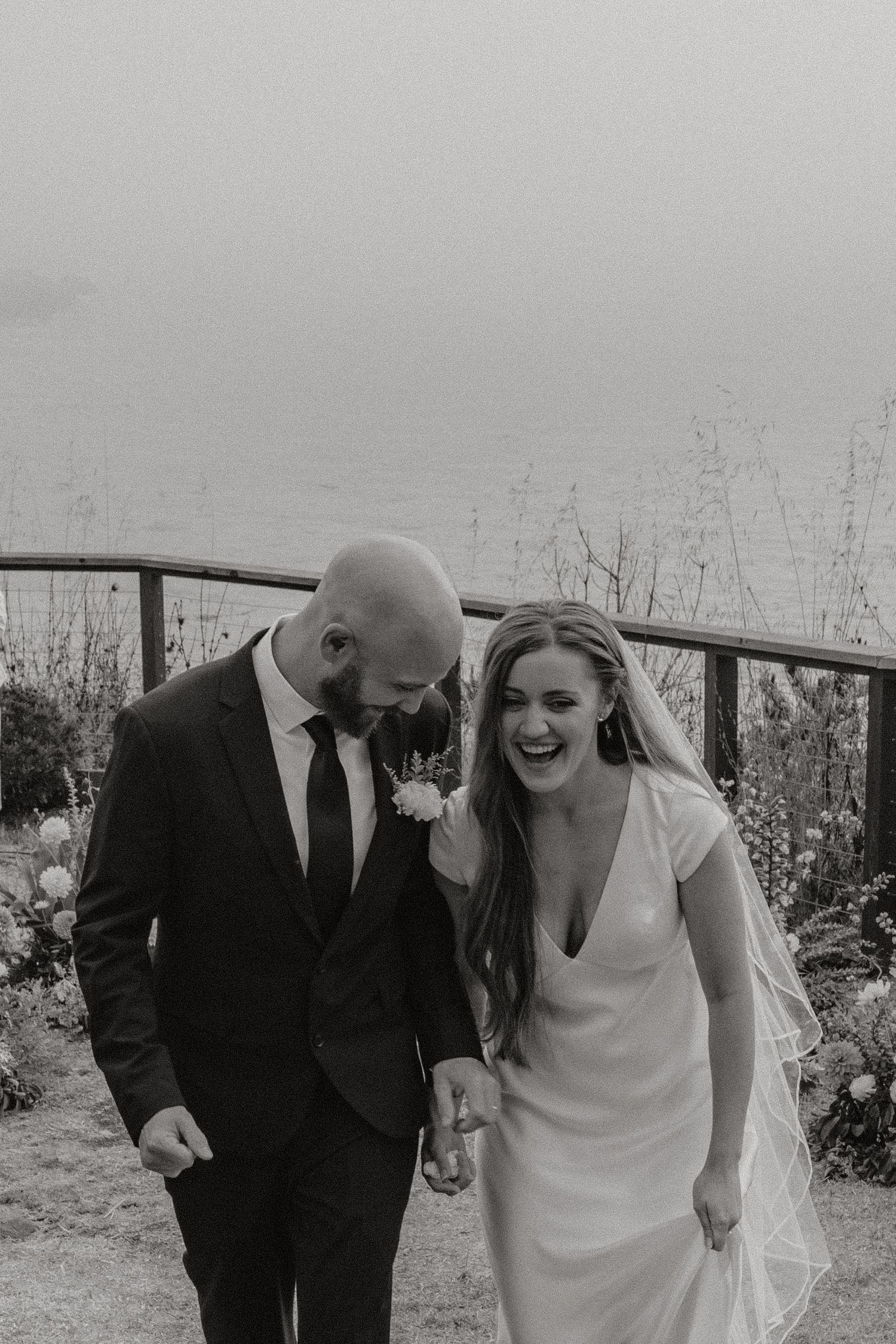 A joyful candid moment captured in black and white during an outdoor wedding celebration.