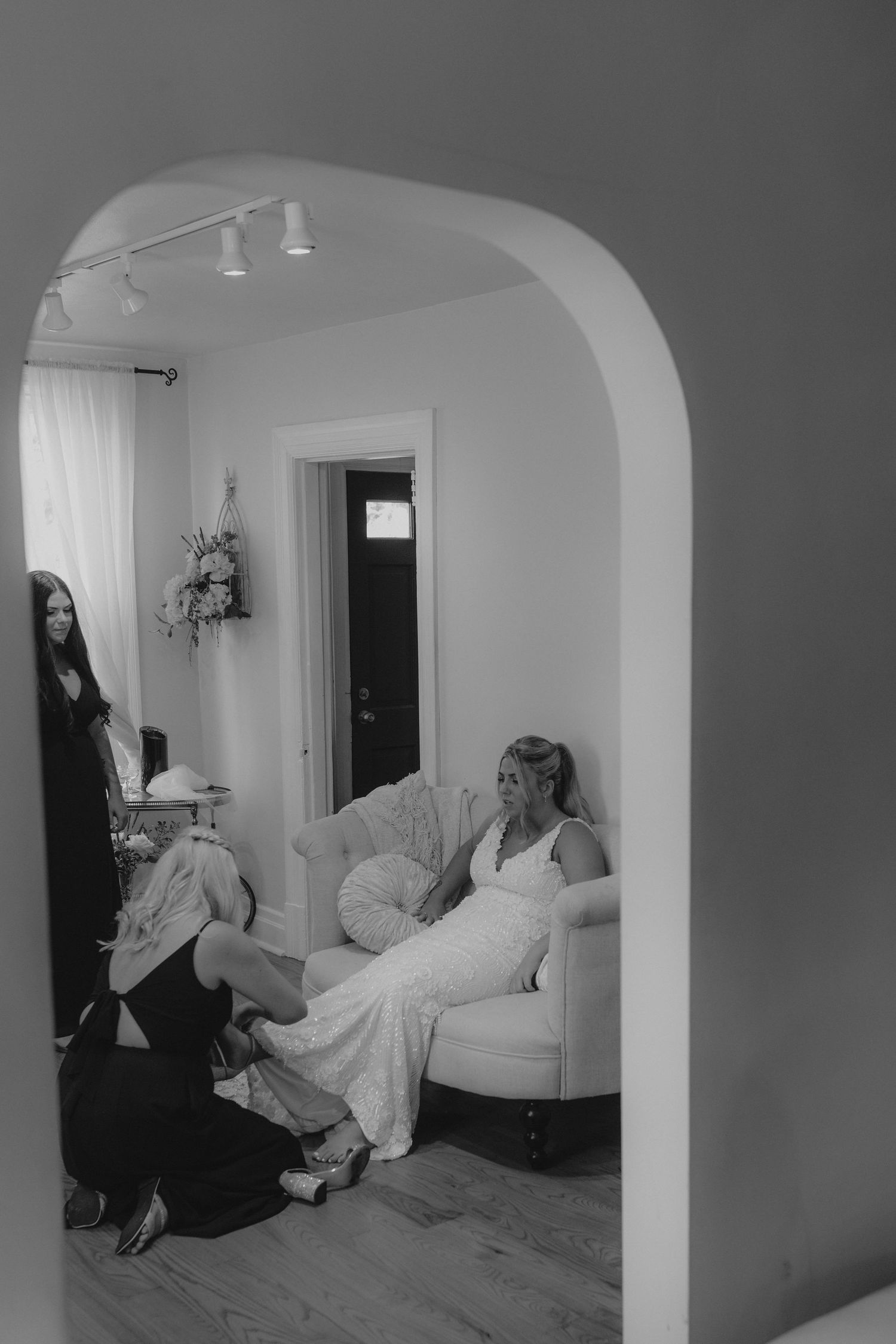 Black and white photo of bridal preparation room with arched doorway and white decor.